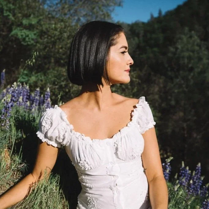 Woman in soft natural light surrounded by flowers.