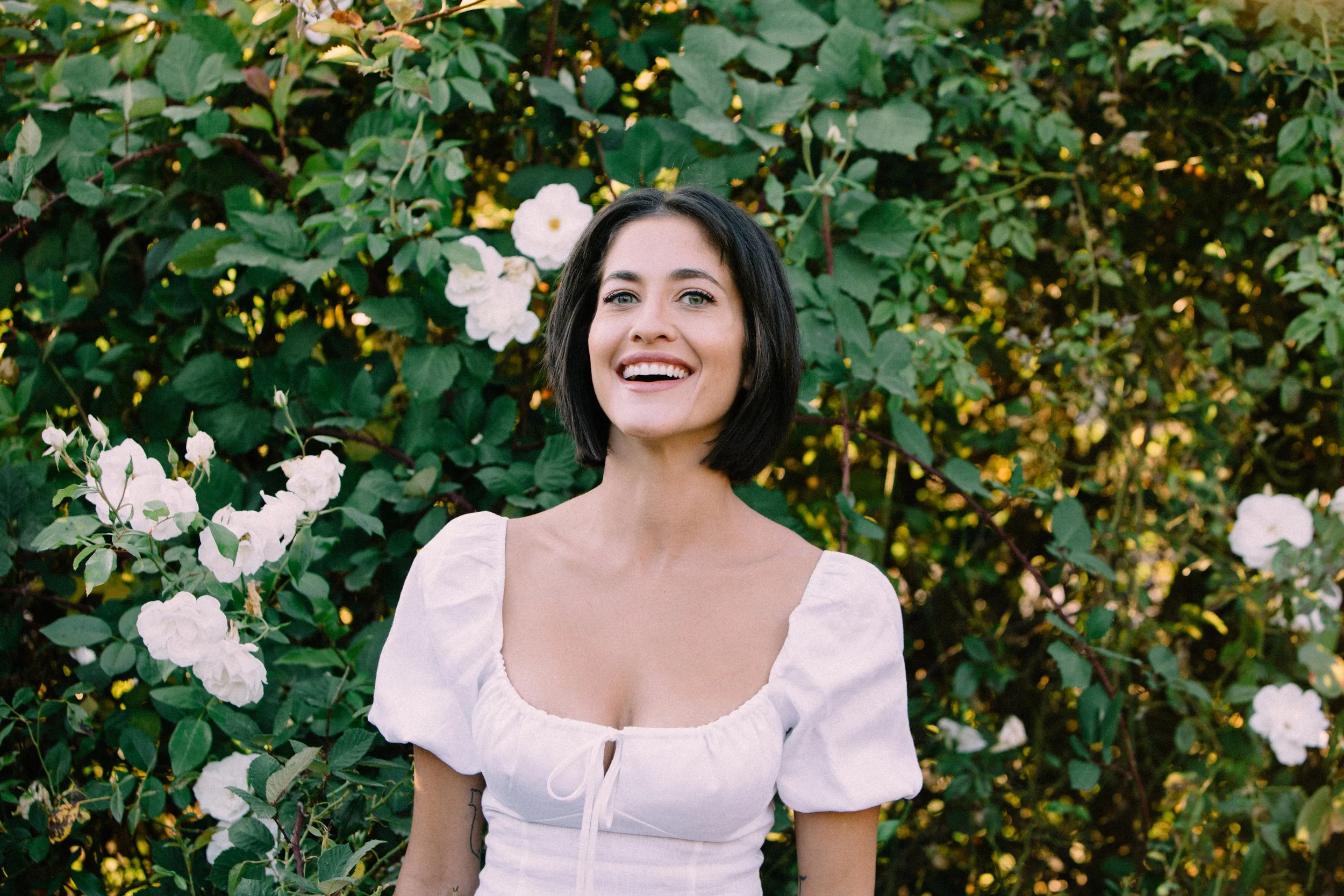 Dahliana Model in the garden with white roses smiling 