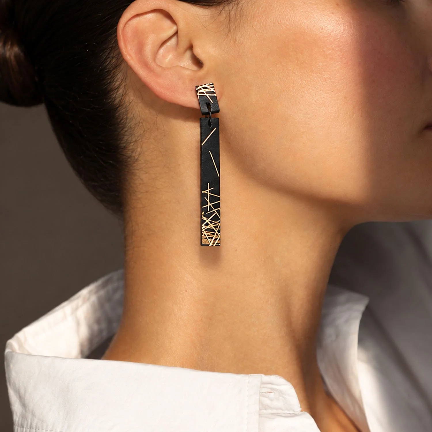 Freehand-lines-leather-drop-earring-black-gold-Tania-Clarke-Hall-modelled-side.jpg