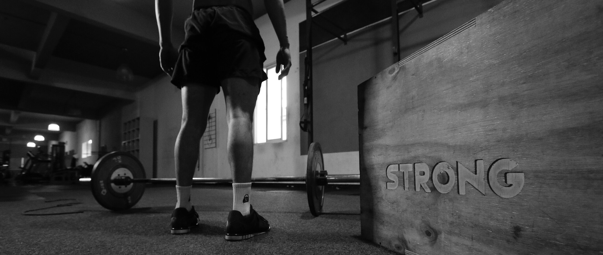 grayscale-photo-of-man-standing-beside-barbell-3112004.jpg