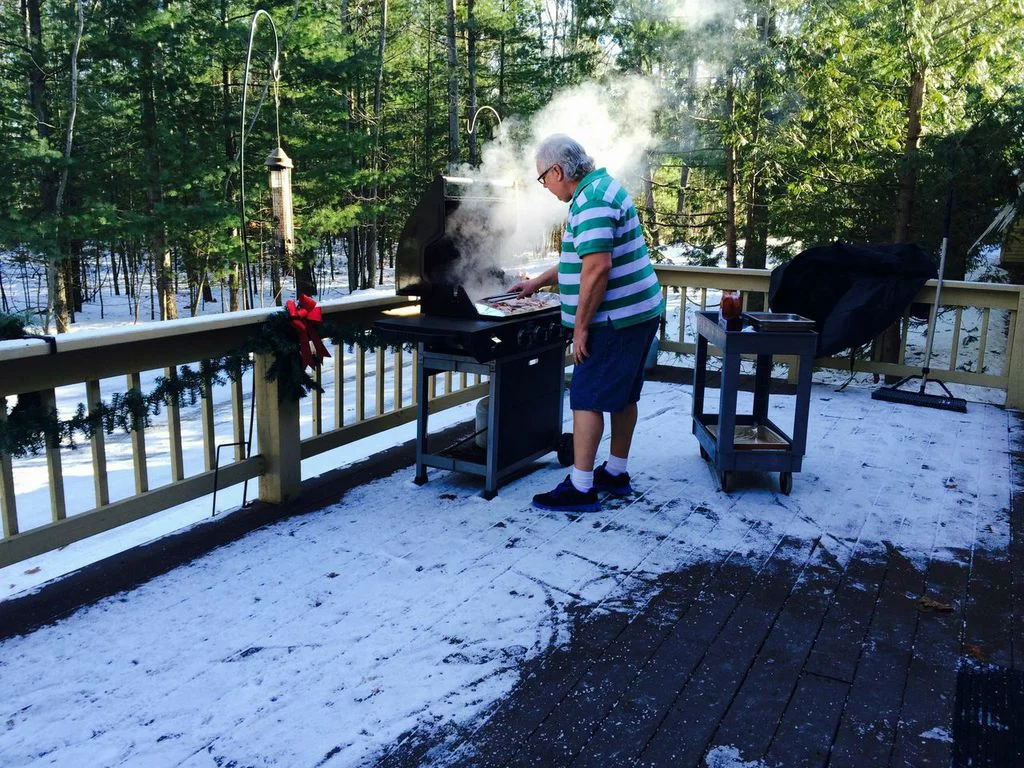 CHEF DEAN TAKES ADVANTAGE OF A SUNNY WINTER DAY TO PREPARE GRILLED CHICKEN FOR OUR RESIDENTS.
