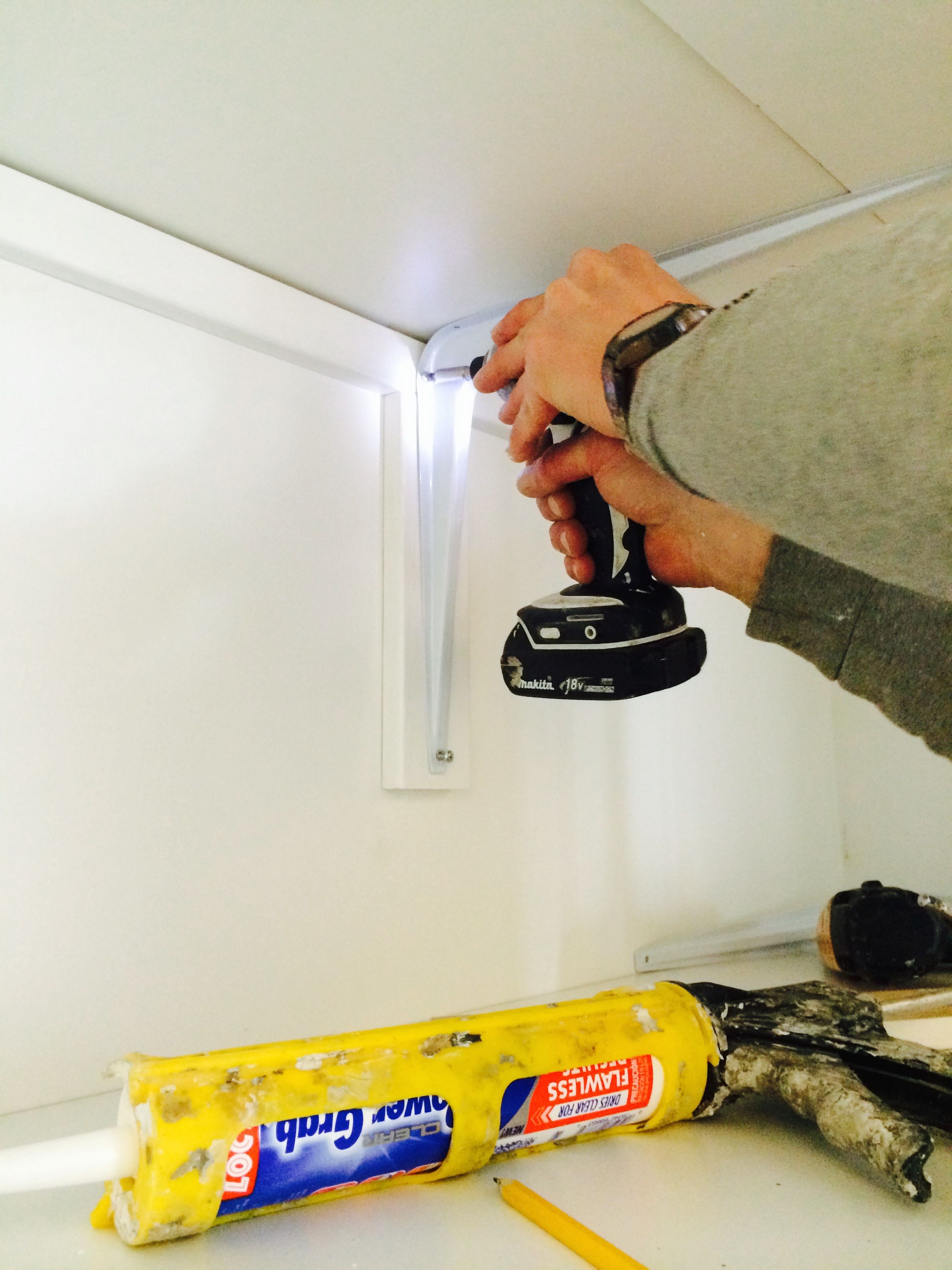 HM adds a shelf-bracket to support a wide shelf that will hold heavy items. (Note the caulk gun used to "wiggle" the construction adhesive onto the cleats before shooting them on.)