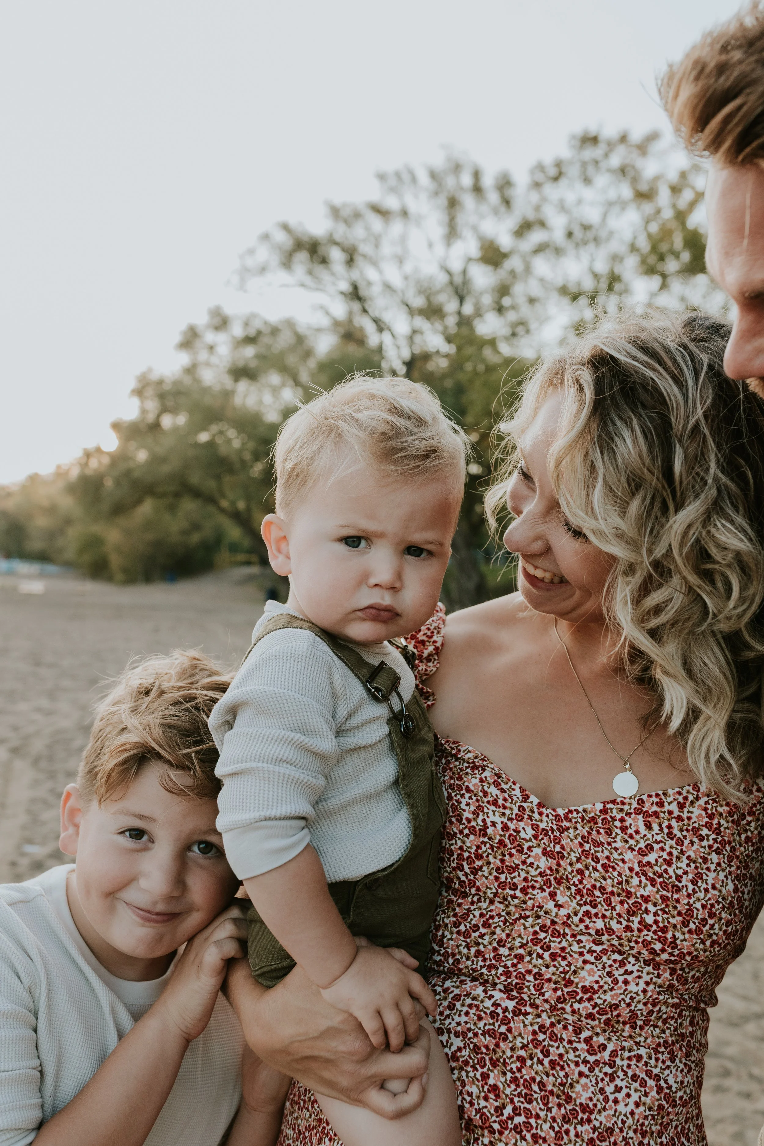 family cuddled up with sons for photos on de la salle beach in georgina ontario