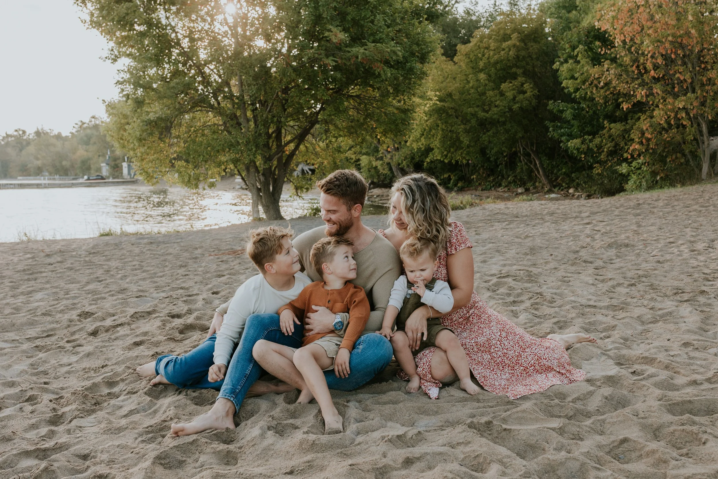 Family sitting together on the beach at sunrise during a Morning Glow Mini Session at De La Salle Beach in Georgina, Ontario.