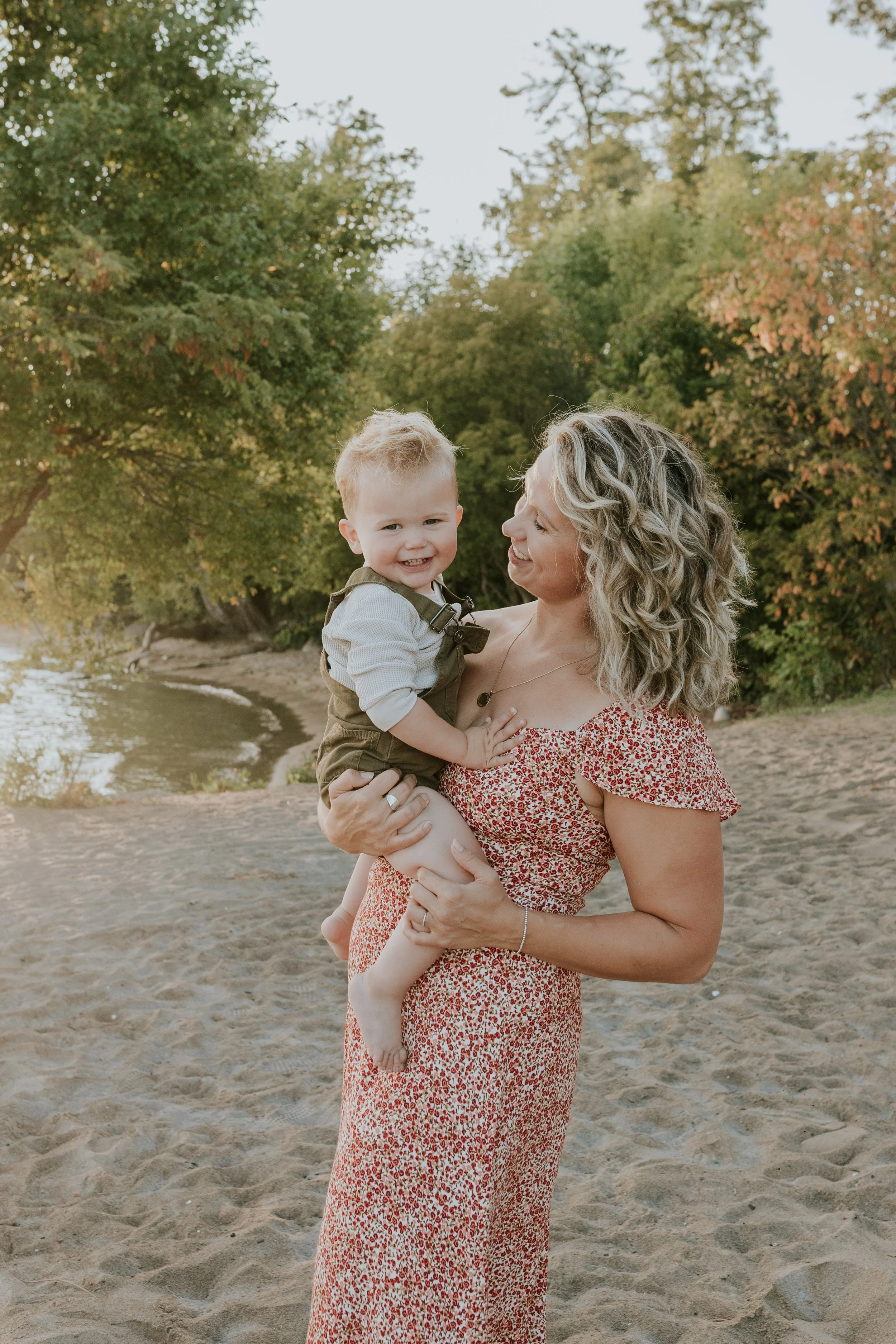 mother and baby boy cuddling in the golden morning light during a family photoshoot at de la salle beach in georgina ontario