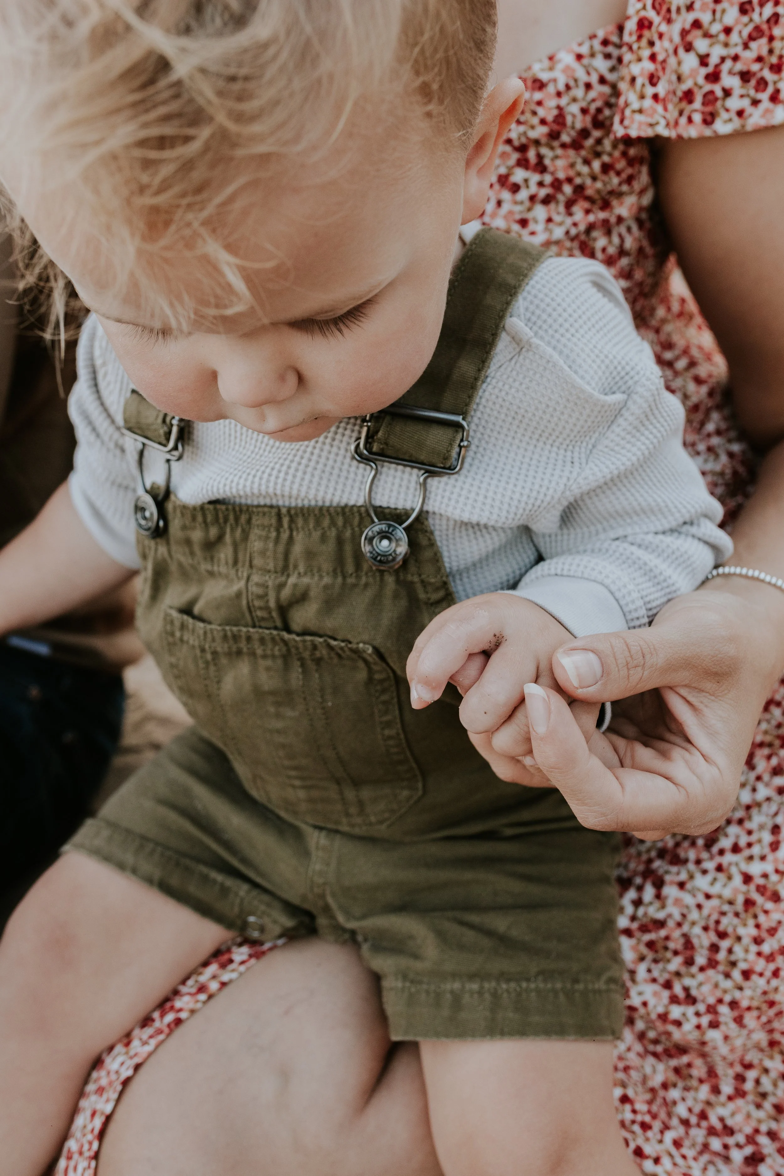 close up for baby boys hand in his mothers hand during a family photo shoot at de la salle beach in georgina ontario