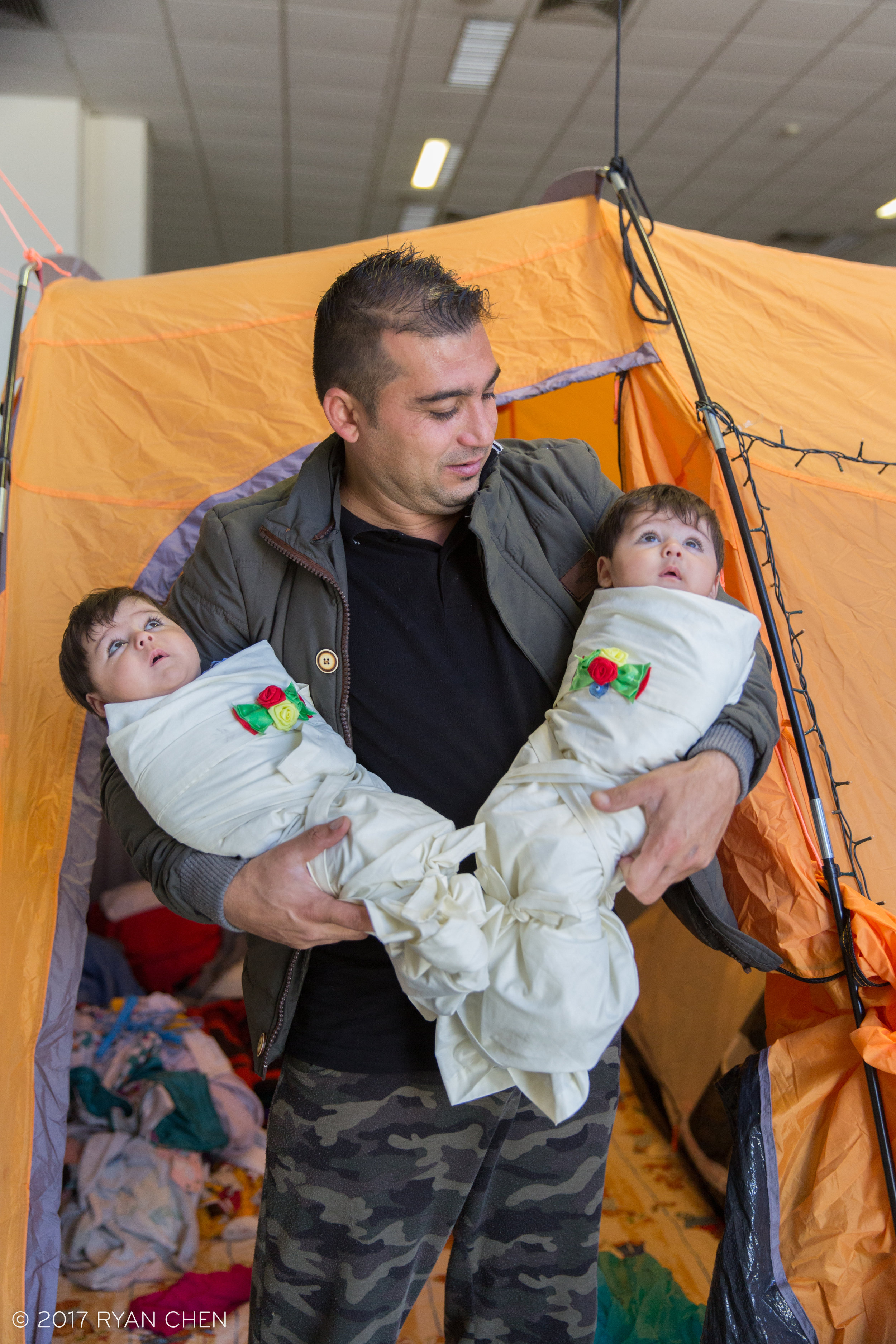 Ajmal, an Afghan refugee with his twin daughters in front of his tent in Elliniko camp, Athens.