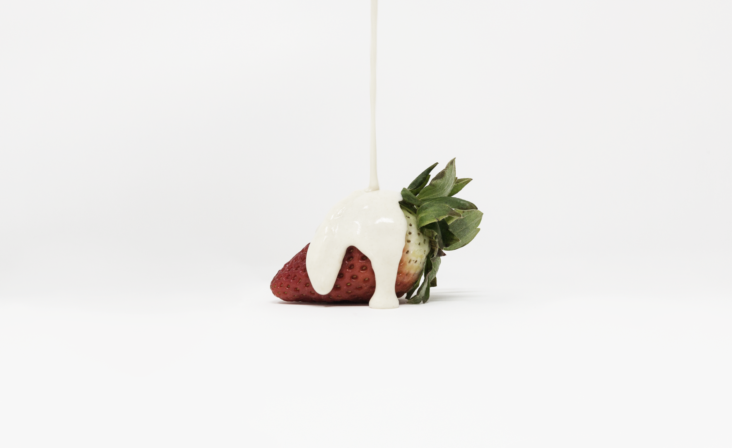 Minimalist, still life photograph of a strawberry covered in a paint-like substance highlighting the value of food, evoking the crucial reflection of the Global Food Crisis