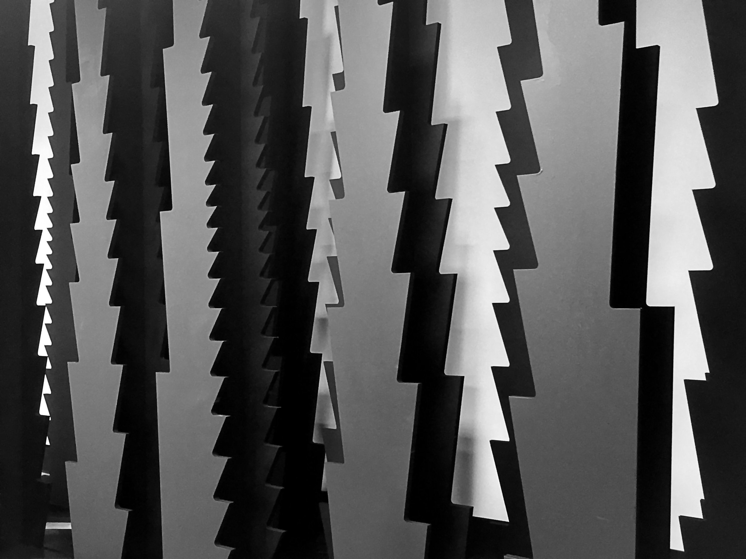 The design of eight conference backdrops – the prerequisites for which included an innovative design approach, striking visual presence, and economy of material means – was used as an opportunity to explore issues of serial variation, digitally derived patterning, and robotic painting. Simultaneously operating as column system, partition wall, architectural scale robotic painting and shelving, neither furniture, nor architecture, Serriform eludes conventional disciplinary definitions. The project’s name, Serriform, comes from the serrated edges that define the silhouette of each column and whose geometries influence the pattern of the painted surfaces. 