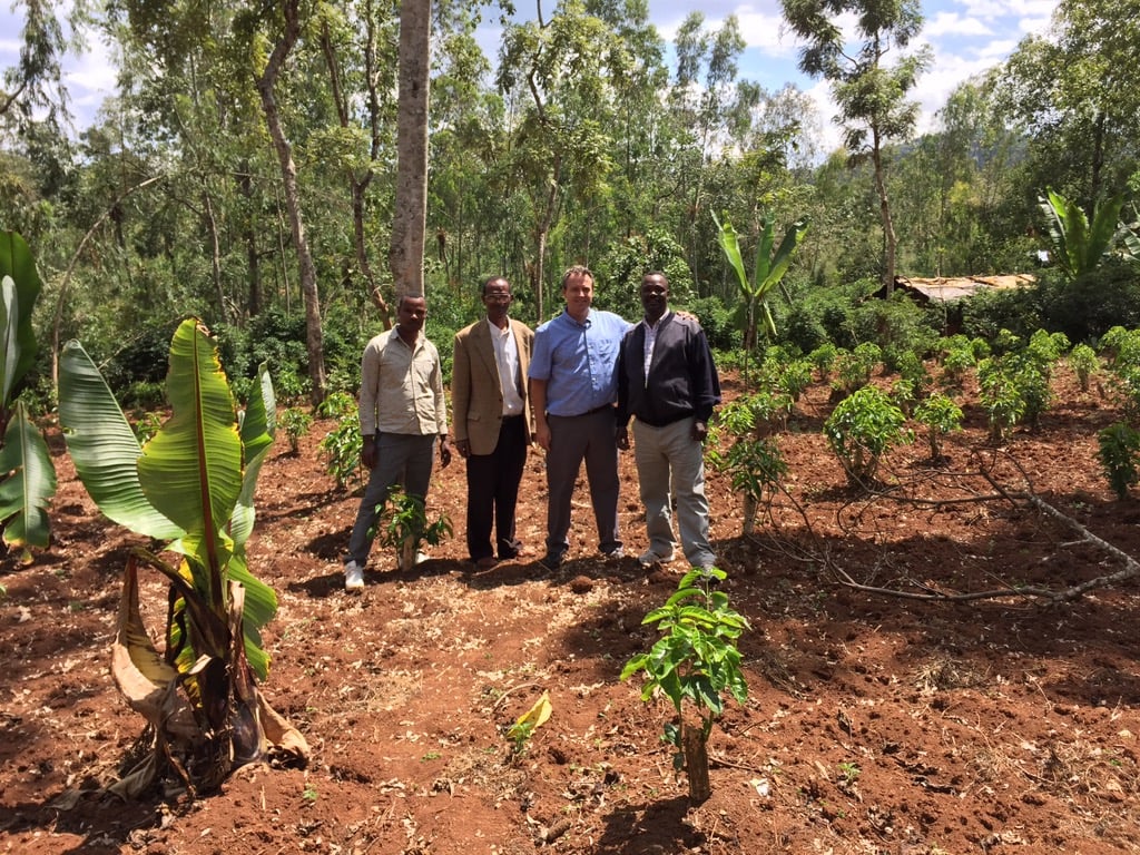 Global CRoss Director Jeff Risk standing in a coffee field with farmers.