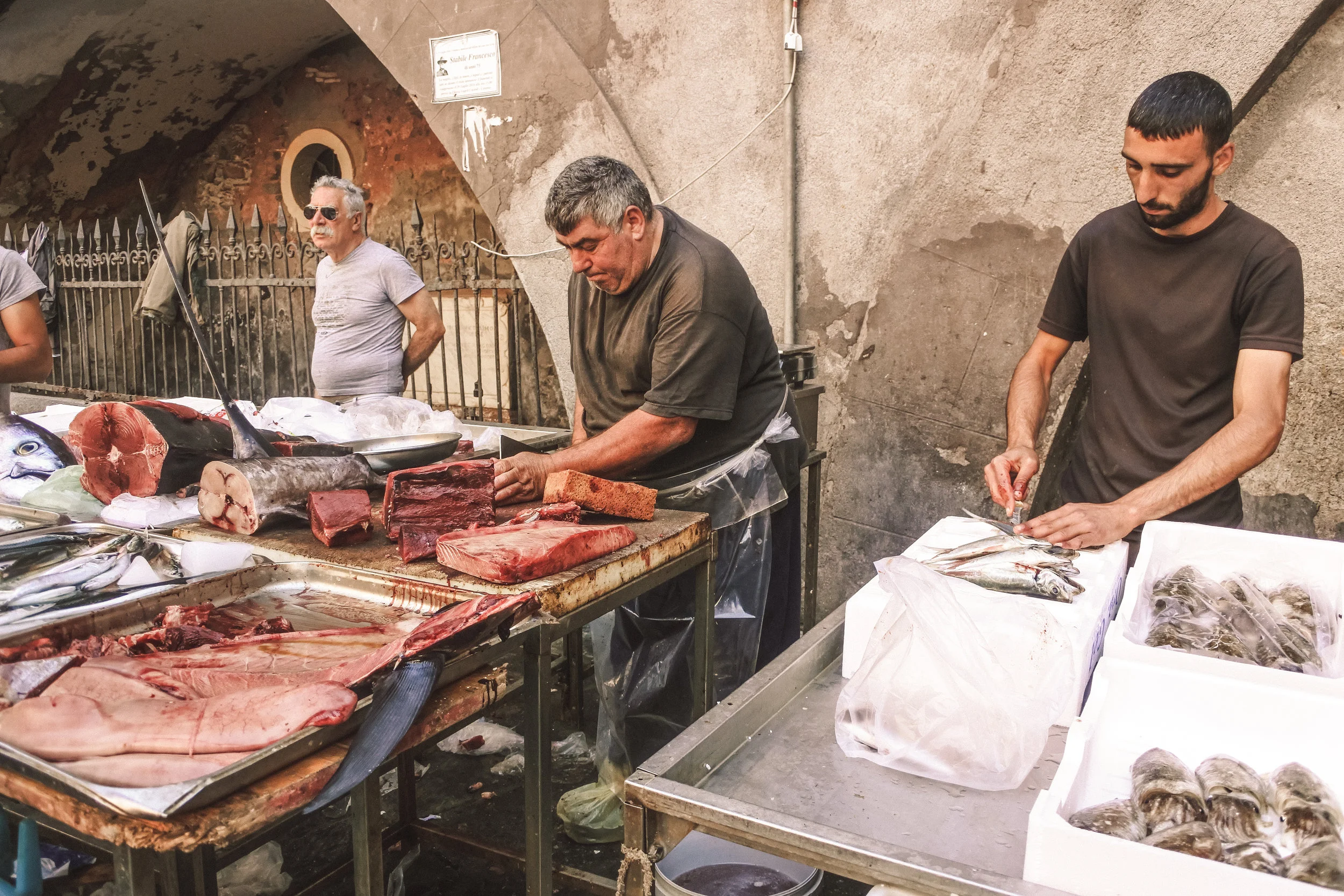 Fish mongers and their catches of the day at La Pescheria in Catania, Italy