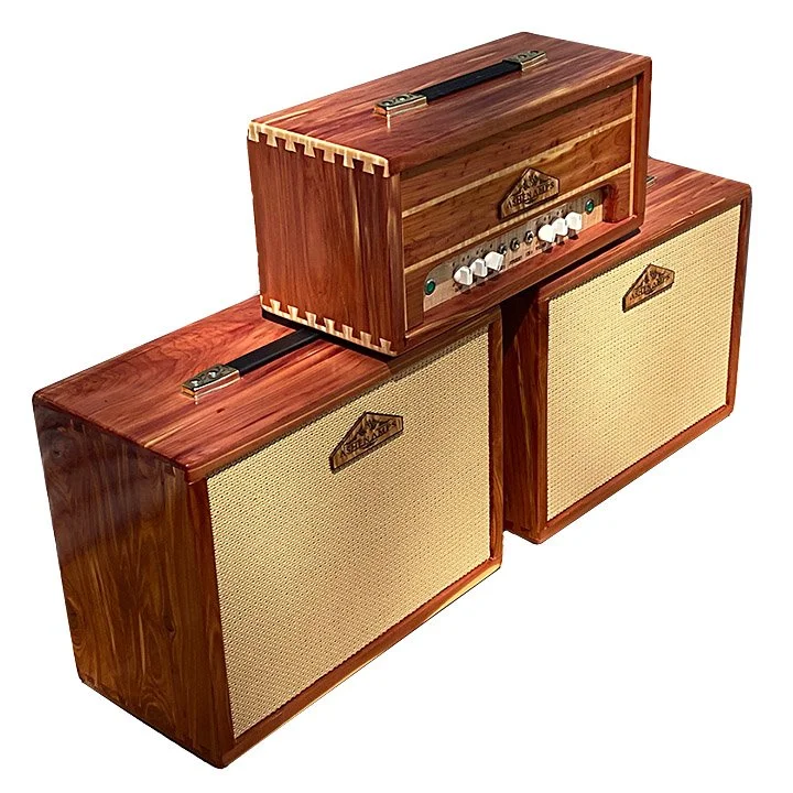A vintage wood guitar set with two large speakers and a tube amplifier head on top, featuring control knobs and a leather handle.