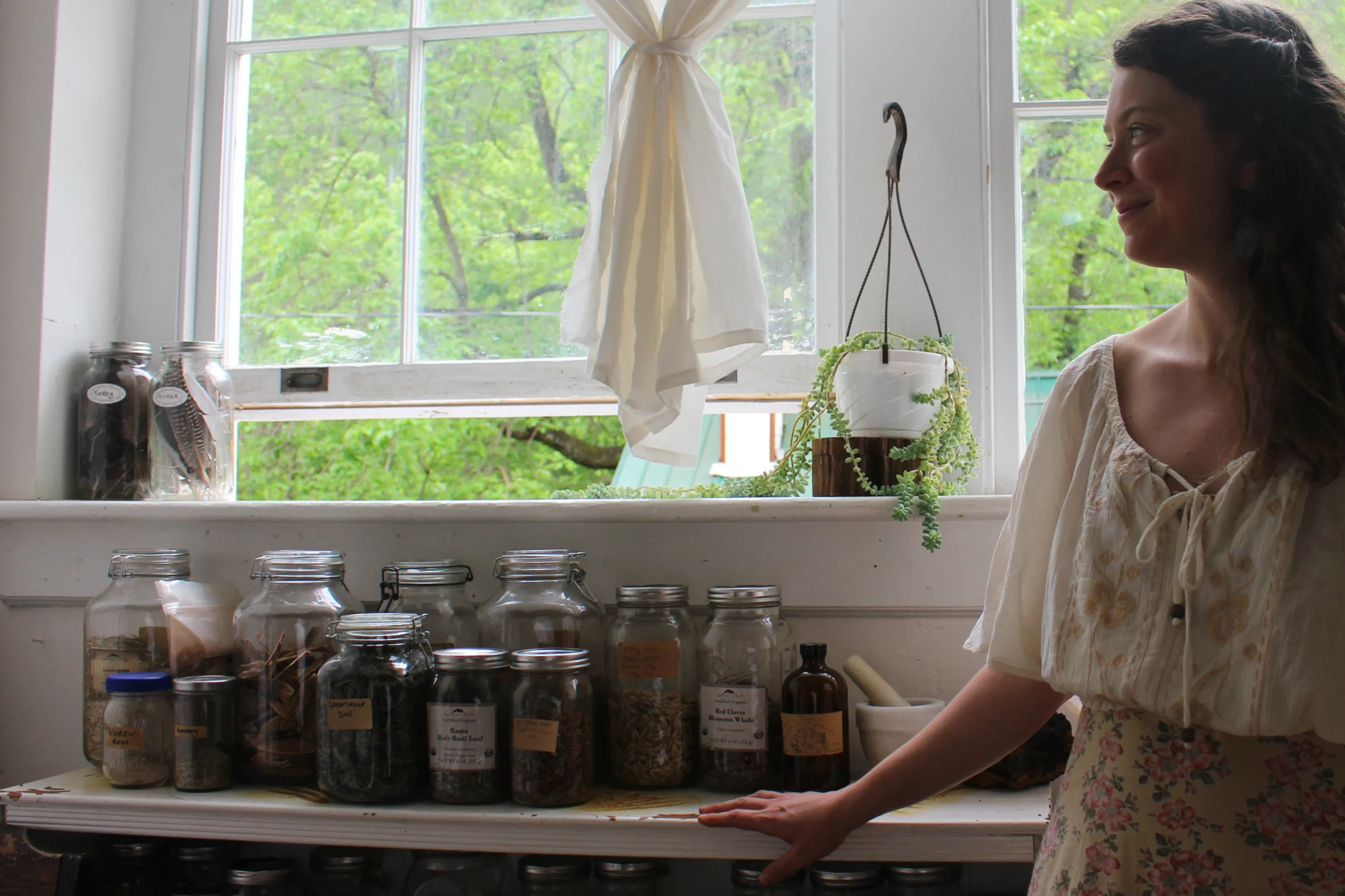 Asia Suler stands beside a stock of dried herbs 