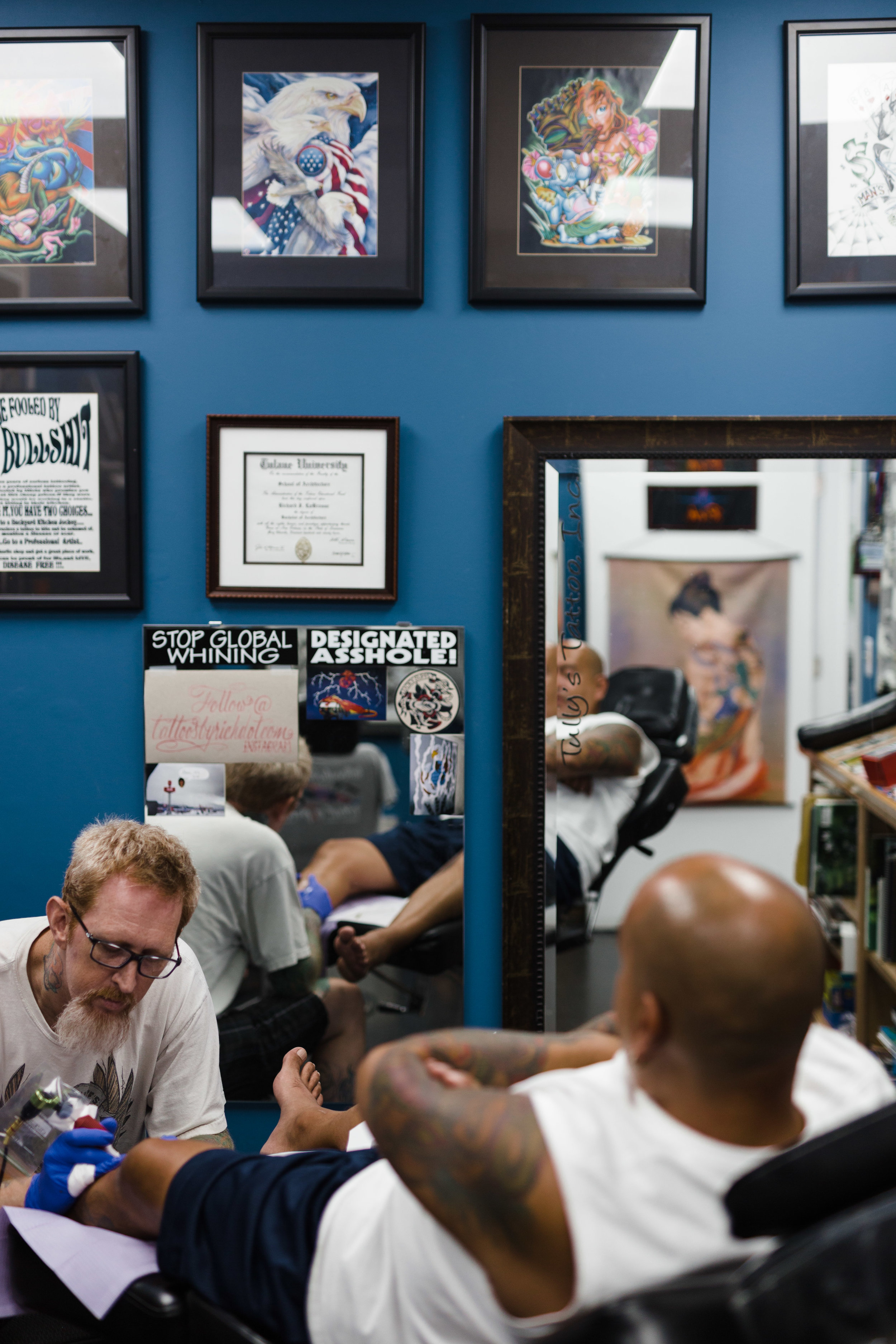 Rich tattoos in his workspace with his Tulane diploma hanging above