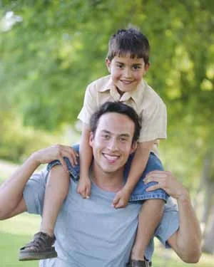 Smiling father with young son smiling on shoulders