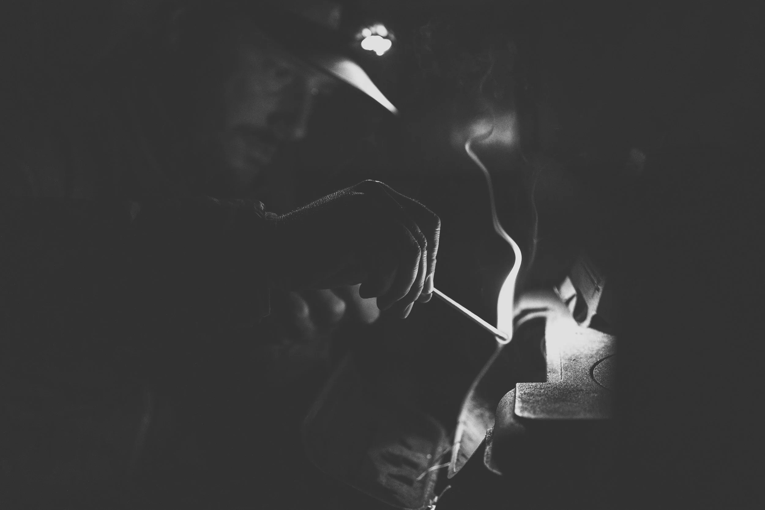 A person using a smartphone in a dark setting, with their face partly illuminated by the screen and light reflecting off their eyeglasses