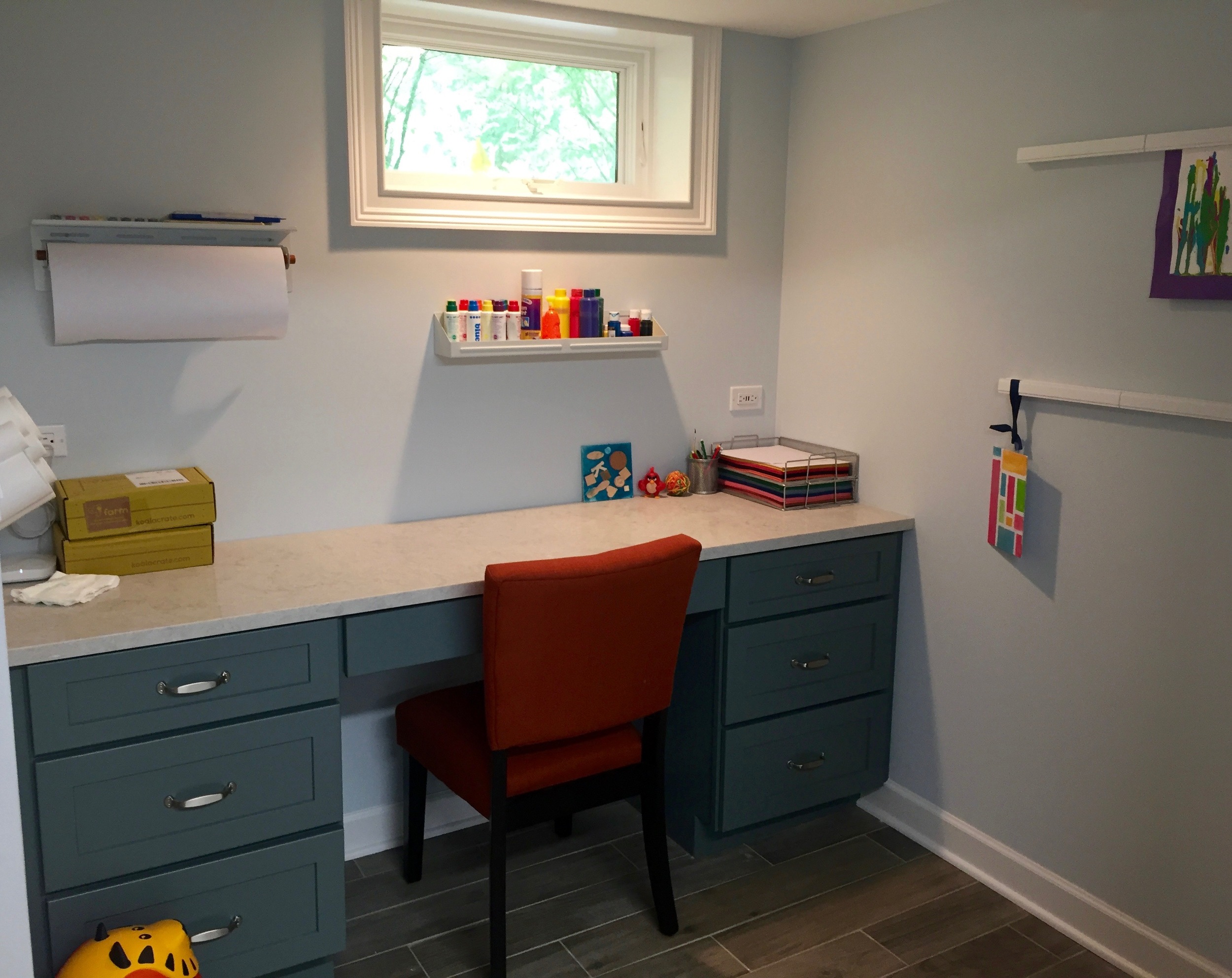 A desk with a quartz top offers storage and durability to resist paint, markers, and glue. Wall-mounted organizers keep art supplies contained above the work surface. Dual outlets with 4 USB ports accommodate electronic devices and, in the future, the space can be converted to a homework station.