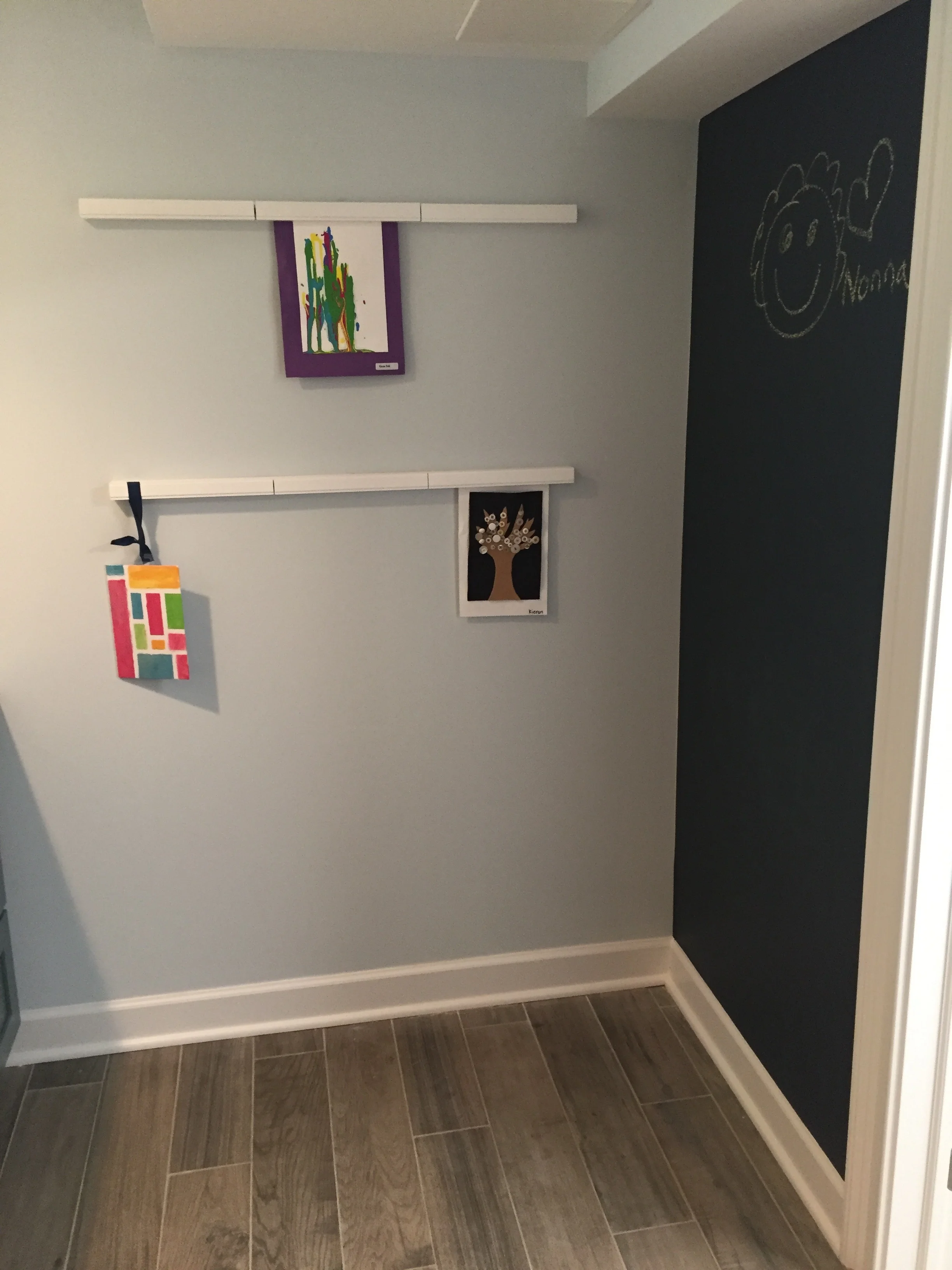 Wall-mounted racks have magnetic locks to hang dry art projects. A chalk-board wall completes the 42 square foot space.