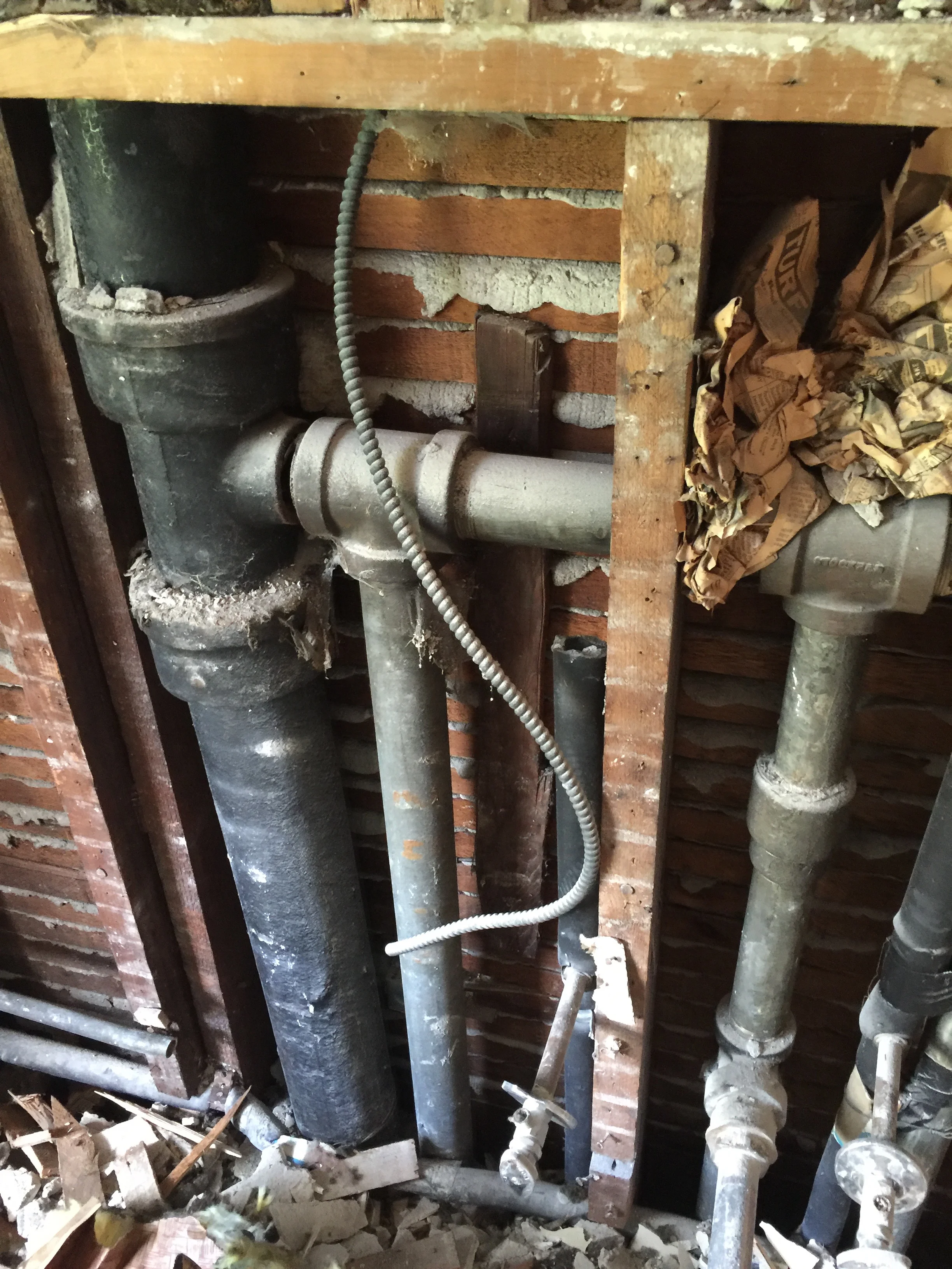 The old iron pipes, some heavily corroded, with a handful of old newspaper evident. When replaced, the new plumbing system should last at least another 100 years. 