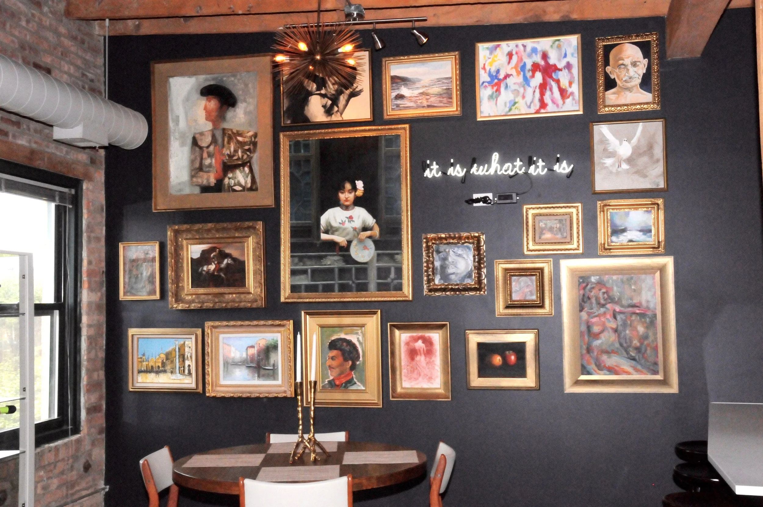 The owner's gallery includes gilt-framed paintings from her international travel and is set against a wall covered in Farrow & Ball's rich midnight blue-black color, Railings, for which we have major love. The neon sign illuminates "it is what is", unexpectedly surrounded by art rather than commonly used as a statement of cold reality or thinly disguised disappointment. Beauty is what it is, and we would never disagree with that. 