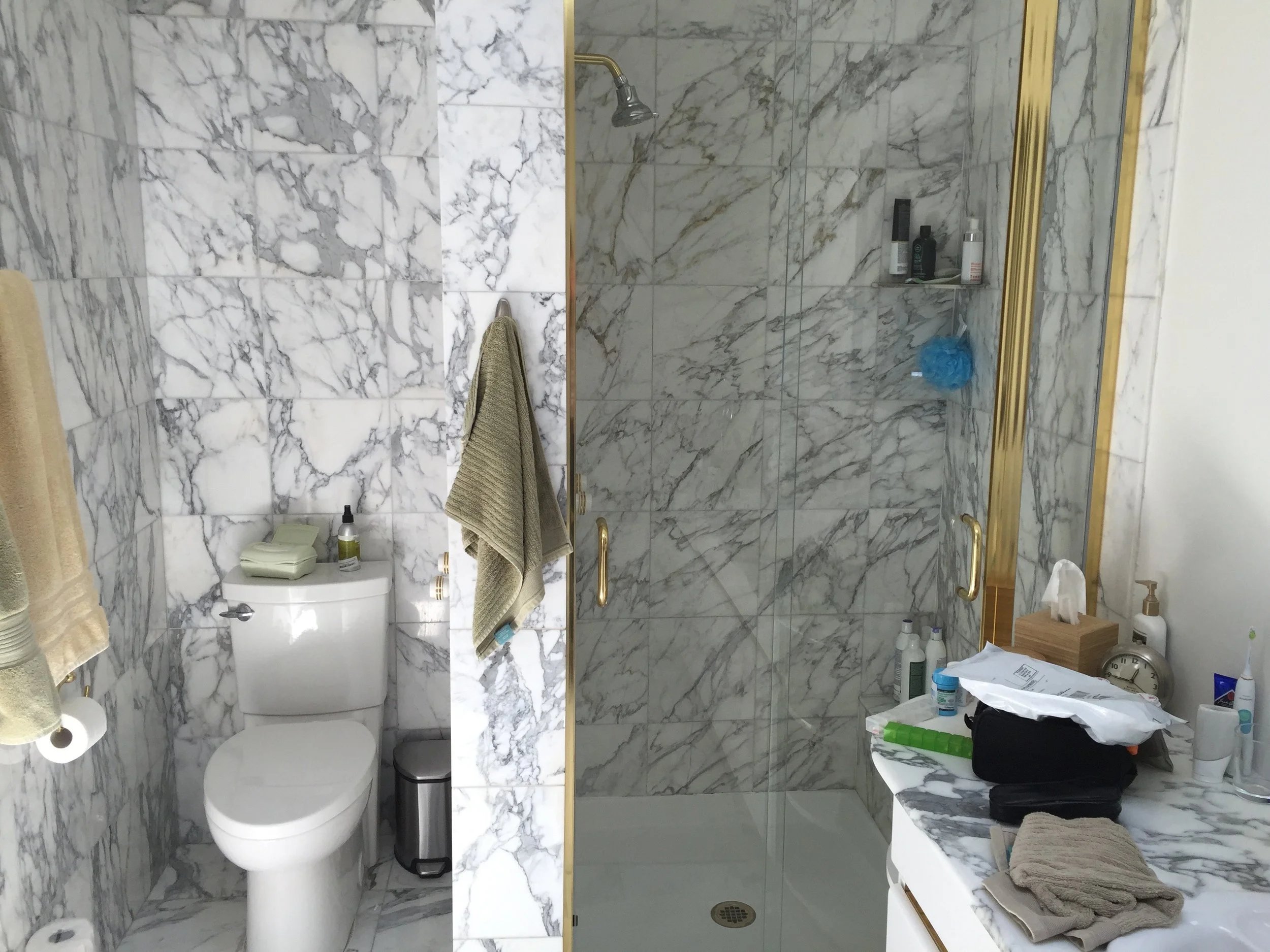 The shiny brass and the same 12x12 marble on nearly every surface tell almost the whole story about the design of this bathroom.