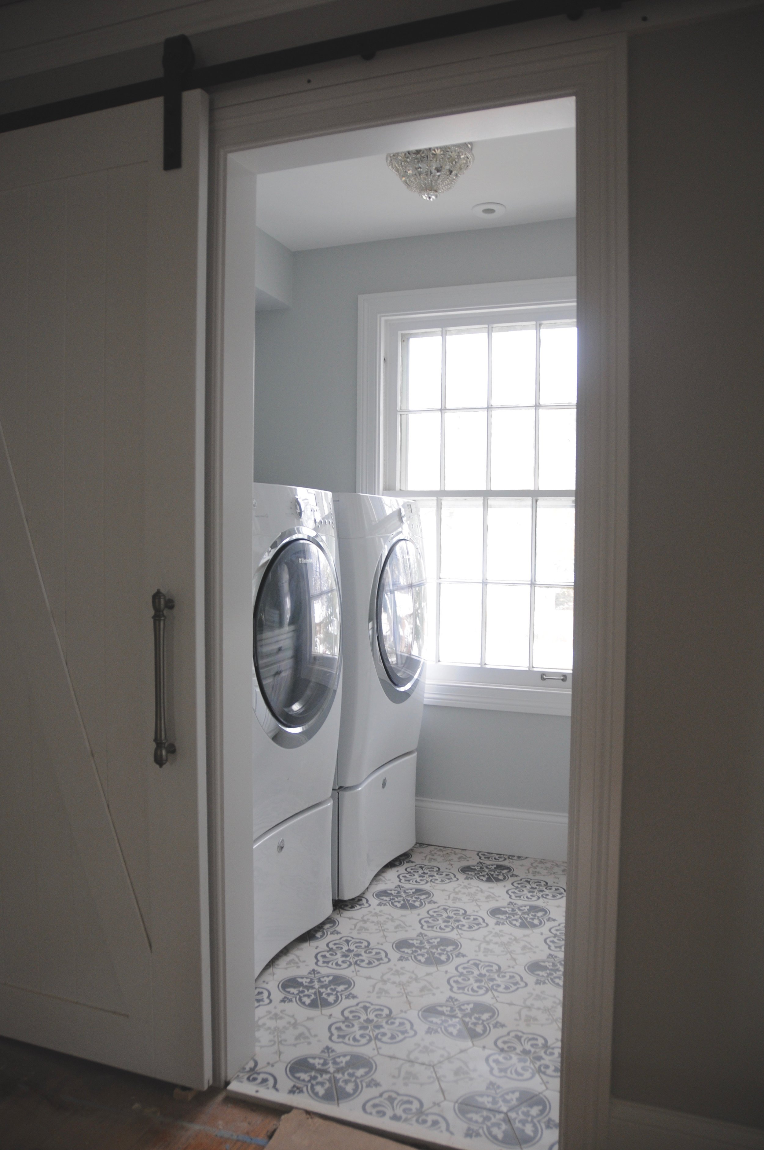 Mounting the machines on pedestals offers good ergonomics for loading and unloading the laundry as well as extra storage. A client let us repurpose the mini crystal flushmount on the ceiling when she no longer needed it. It's the perfect size and a good use of surplus lighting fixtures. Who says your laundry room can't have a little glamour? 