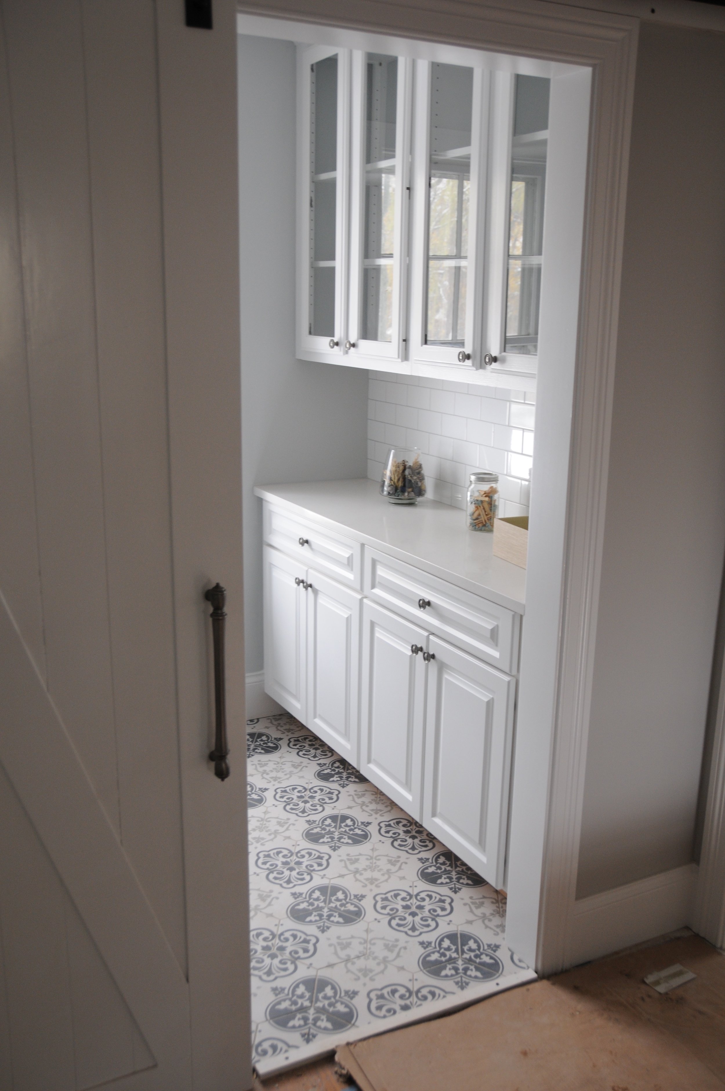 Lower and upper cabinets with a durable quartz top help make this compact laundry room punch above its weight class with regard to elegant storage. Yet another generous client donated the glass door cabinets, and repurposing them here was better than sending them to the landfill.