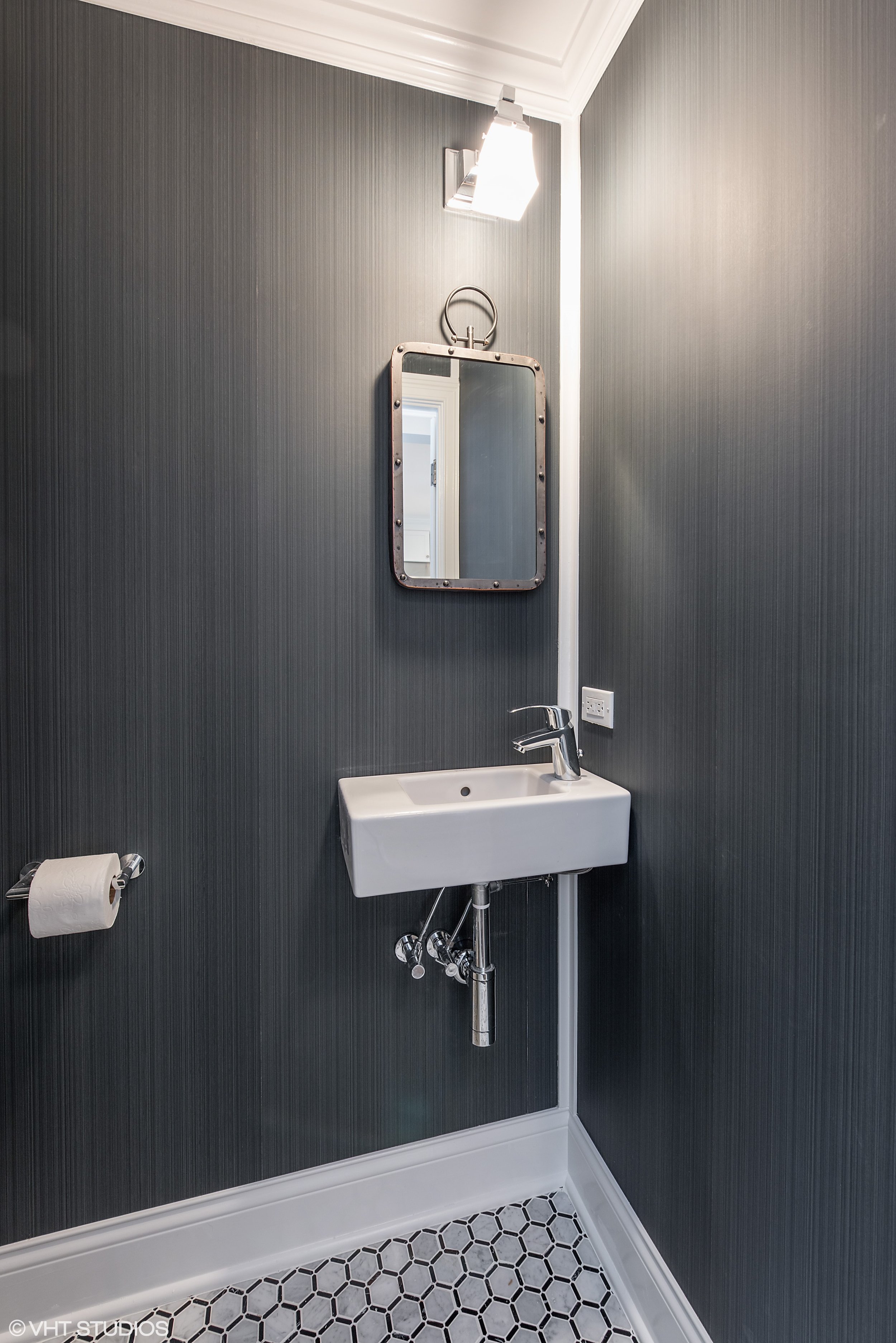 A small powder room is a fun challenge, and there is some limit to what can be done in a 44" x 44" room once the toilet is installed. The dramatic Farrow & Ball wallpaper created a dragged-paint effect and accentuates the height of the bathroom. 