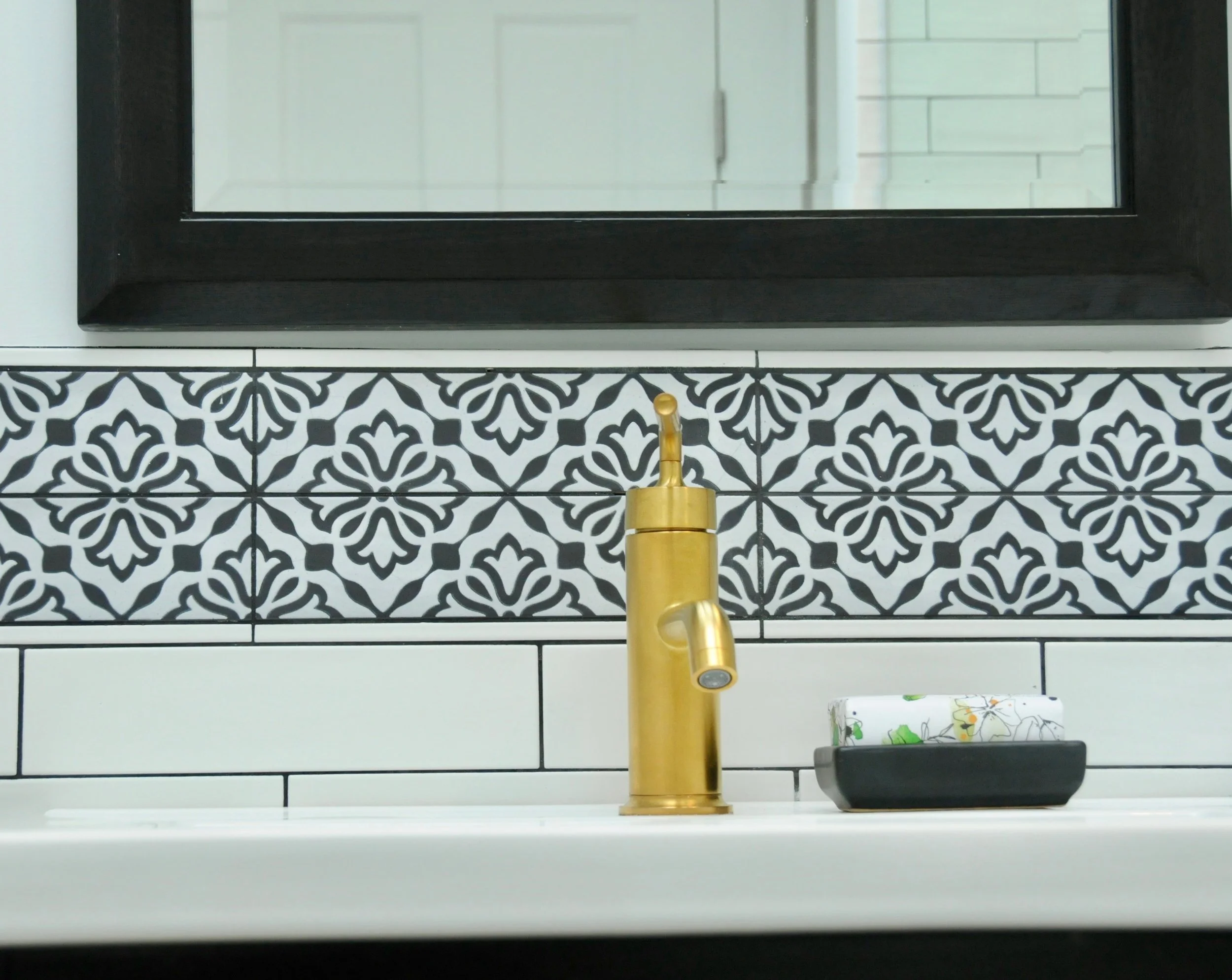 Black & white doesn't have to be old-fashioned or overtly masculine. Here we used an elongated white subway tile to update a classic look and softened the visuals with a decorative backsplash.