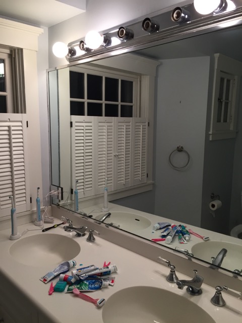 Half of the old vanity with surprisingly little useful storage, poor lighting, and no medicine cabinets.