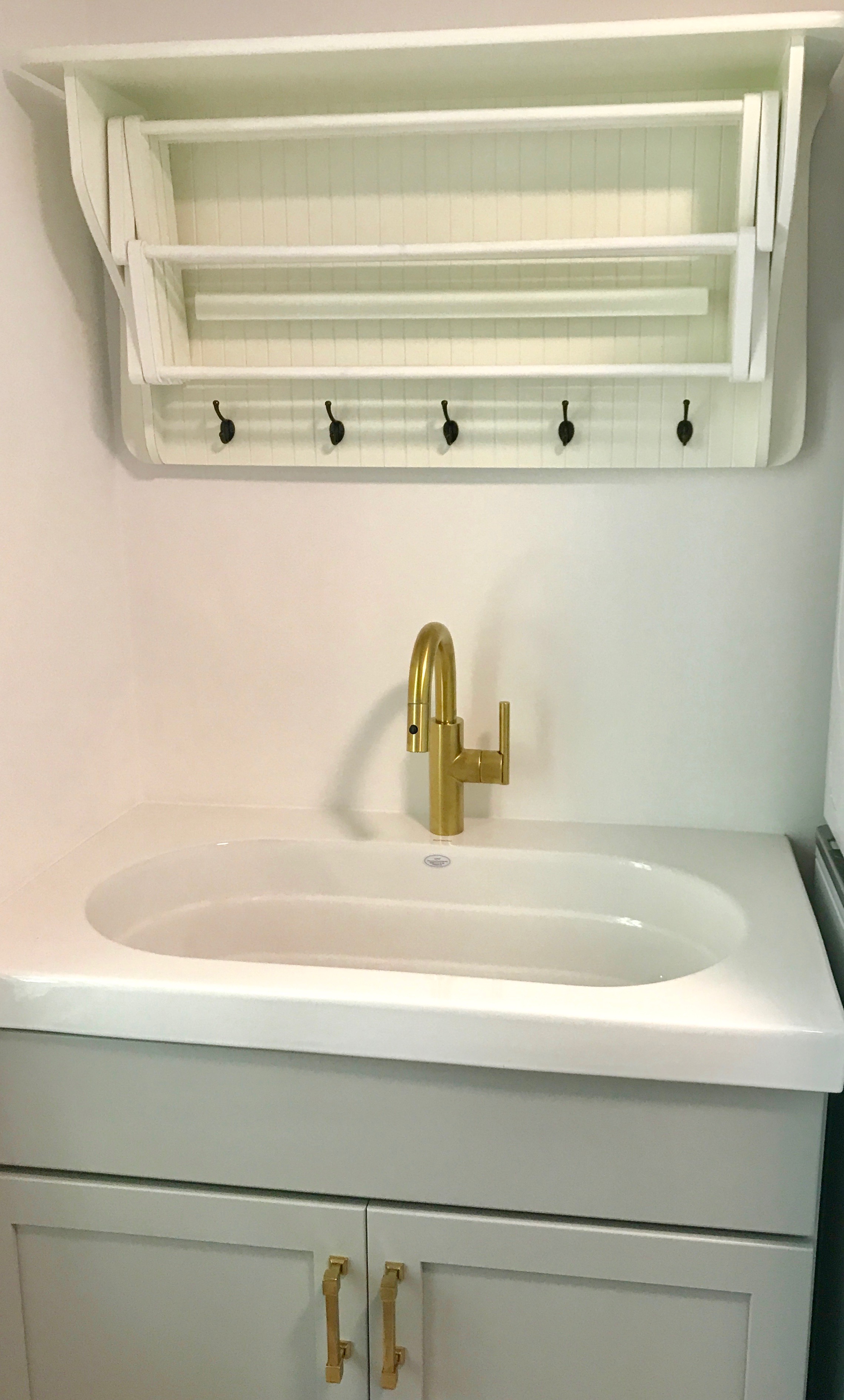 A deep utility sink and drying rack next to the laundry machines. 