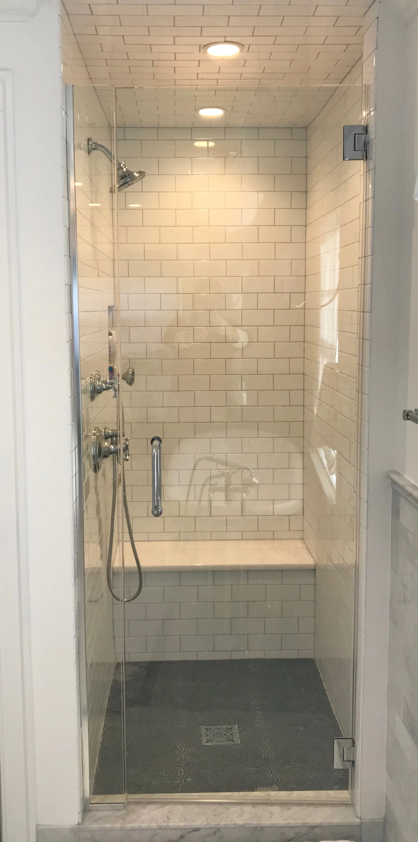 Kallista Bellis shower pieces and a white quartzite bench match the vanity top and sink faucets. 