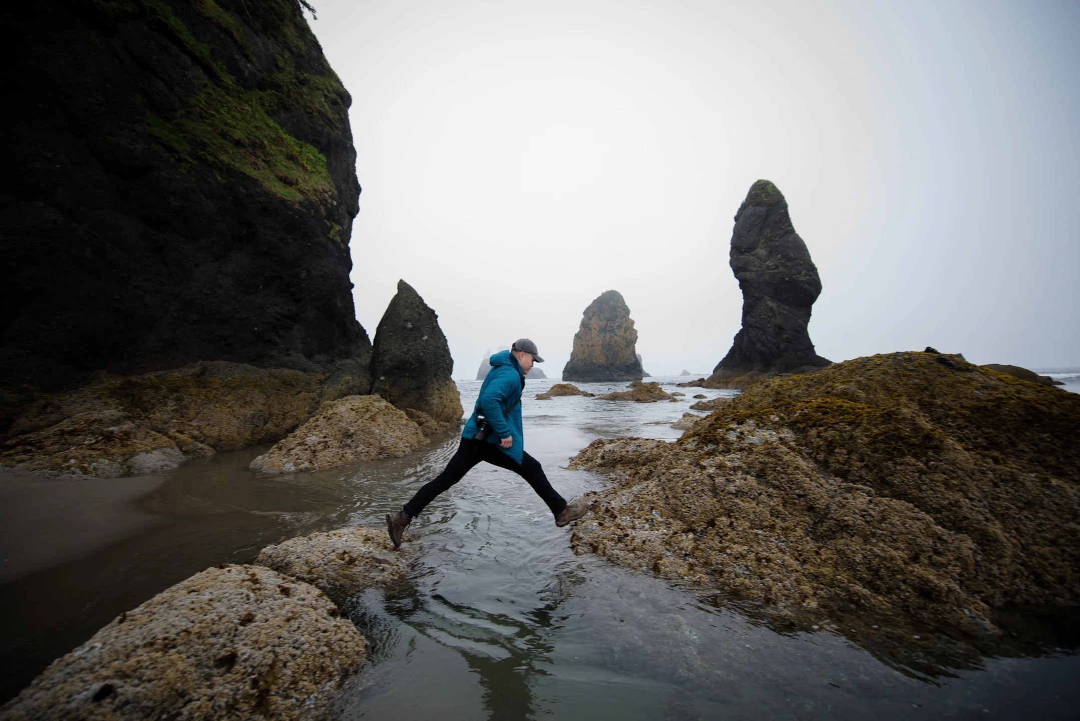 Jeffrey Le jumps between two rocks at Point of the Arches at Shi Shi Beach along the Olympic Peninsula Pacific Northwest Coast Washington