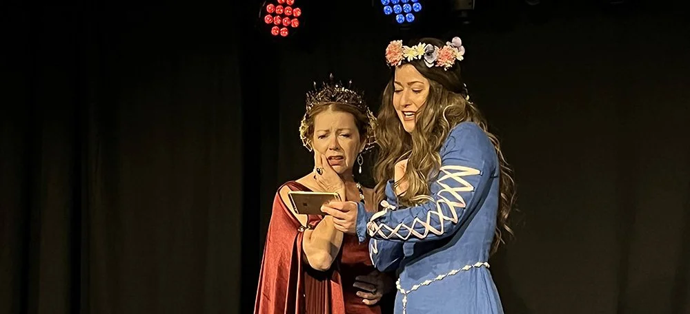 two women in medieval dress looking at a cell phone