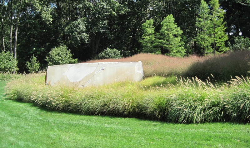 Ornamental grasses surround a stone sculpture.