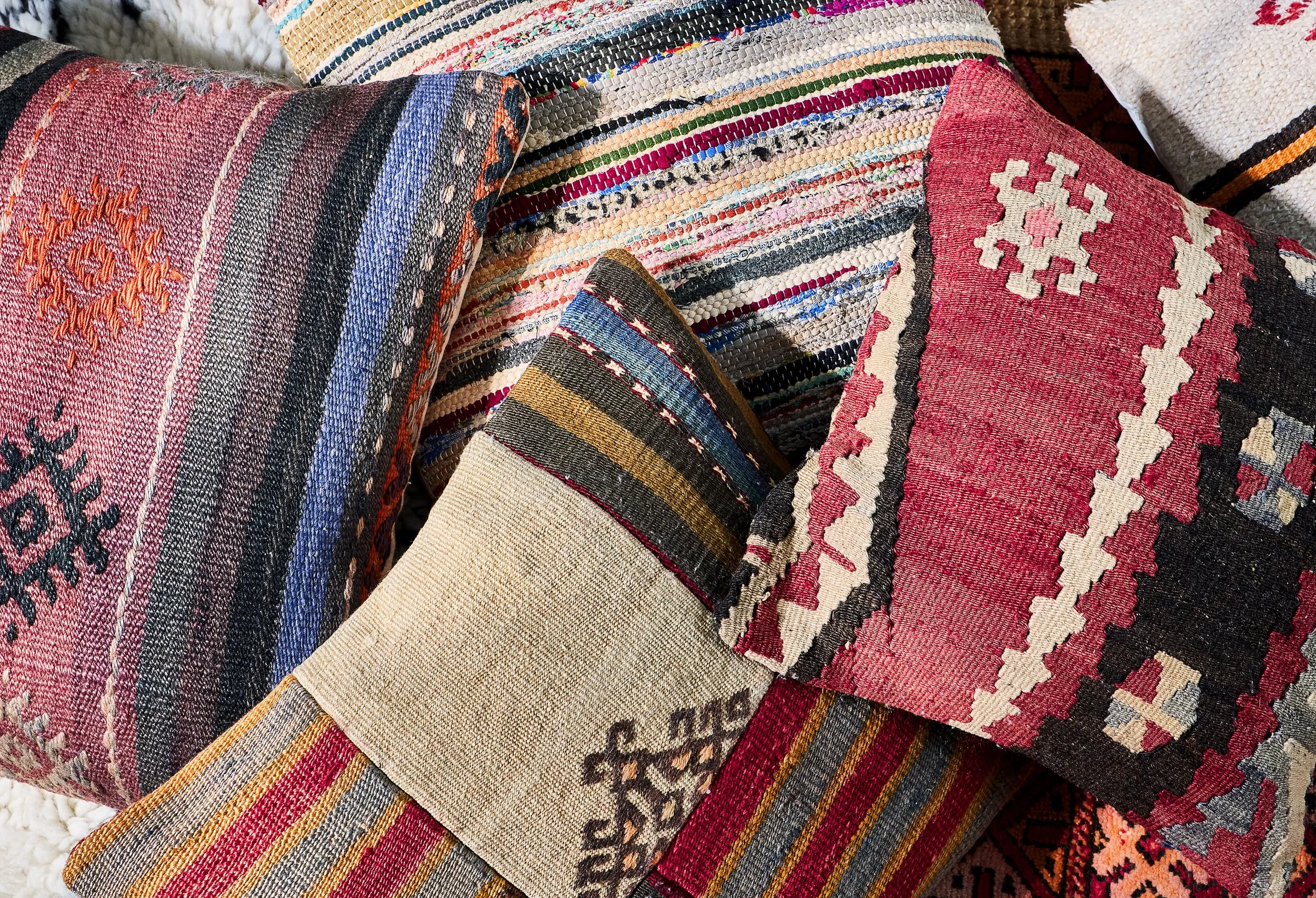 Close-up of multicolored woven textured rugs with various geometric patterns and stripes.