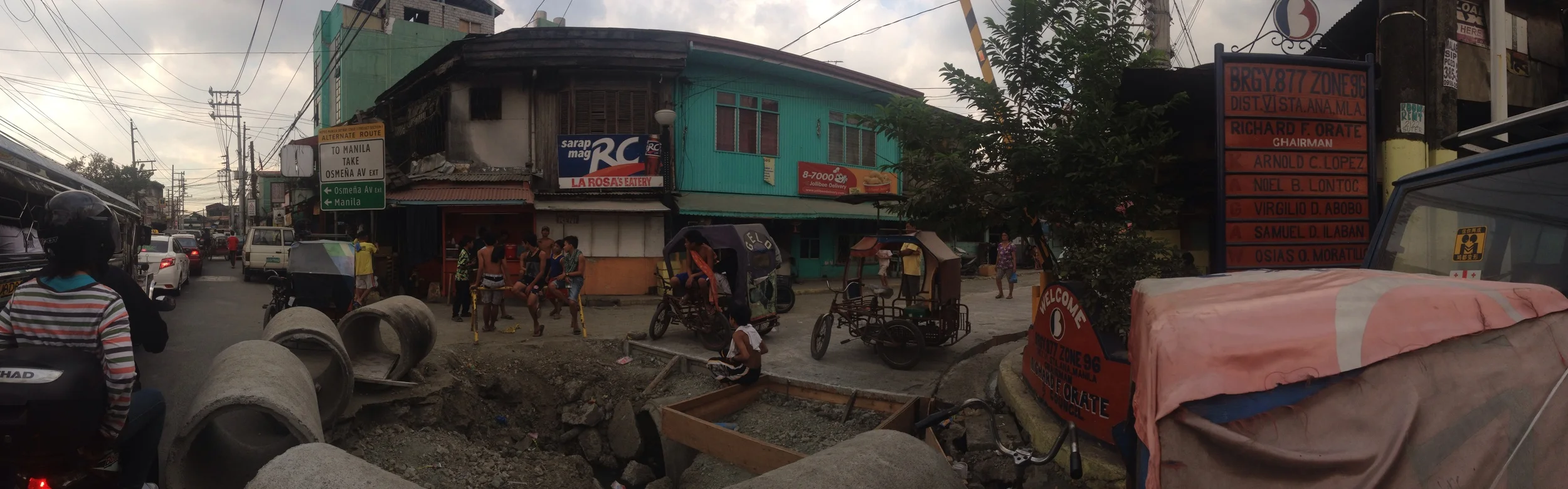 Kids hang out on a bar of scaffolding by a construction site. Seems the construction blocks traffic and the street end becomes a small plaza space where people can gather.