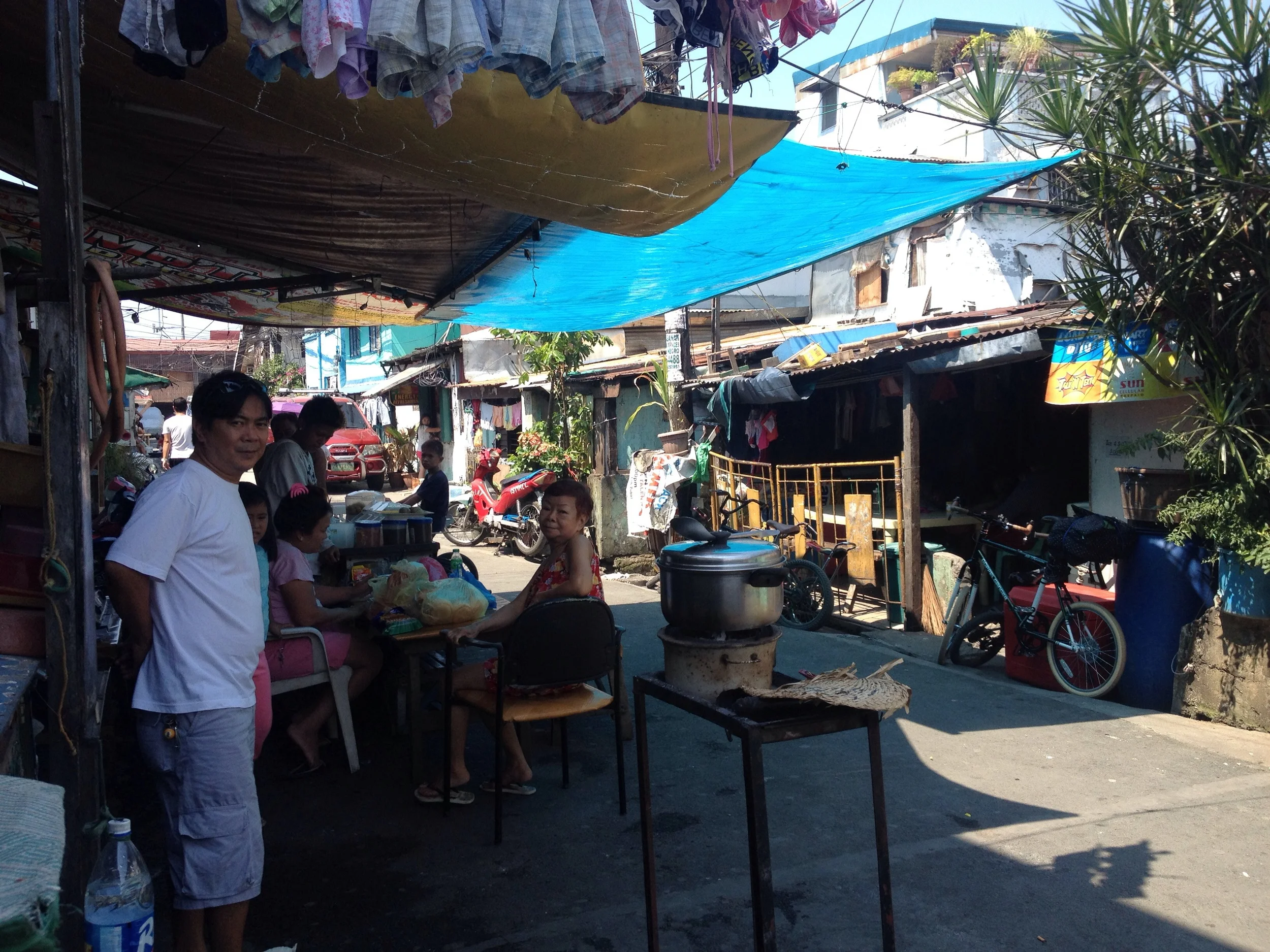 Noel de Jesus and his family attach tarps across the street to create shade for the street stall outside their house. They let me rest there for a while to escape the hot sun. 