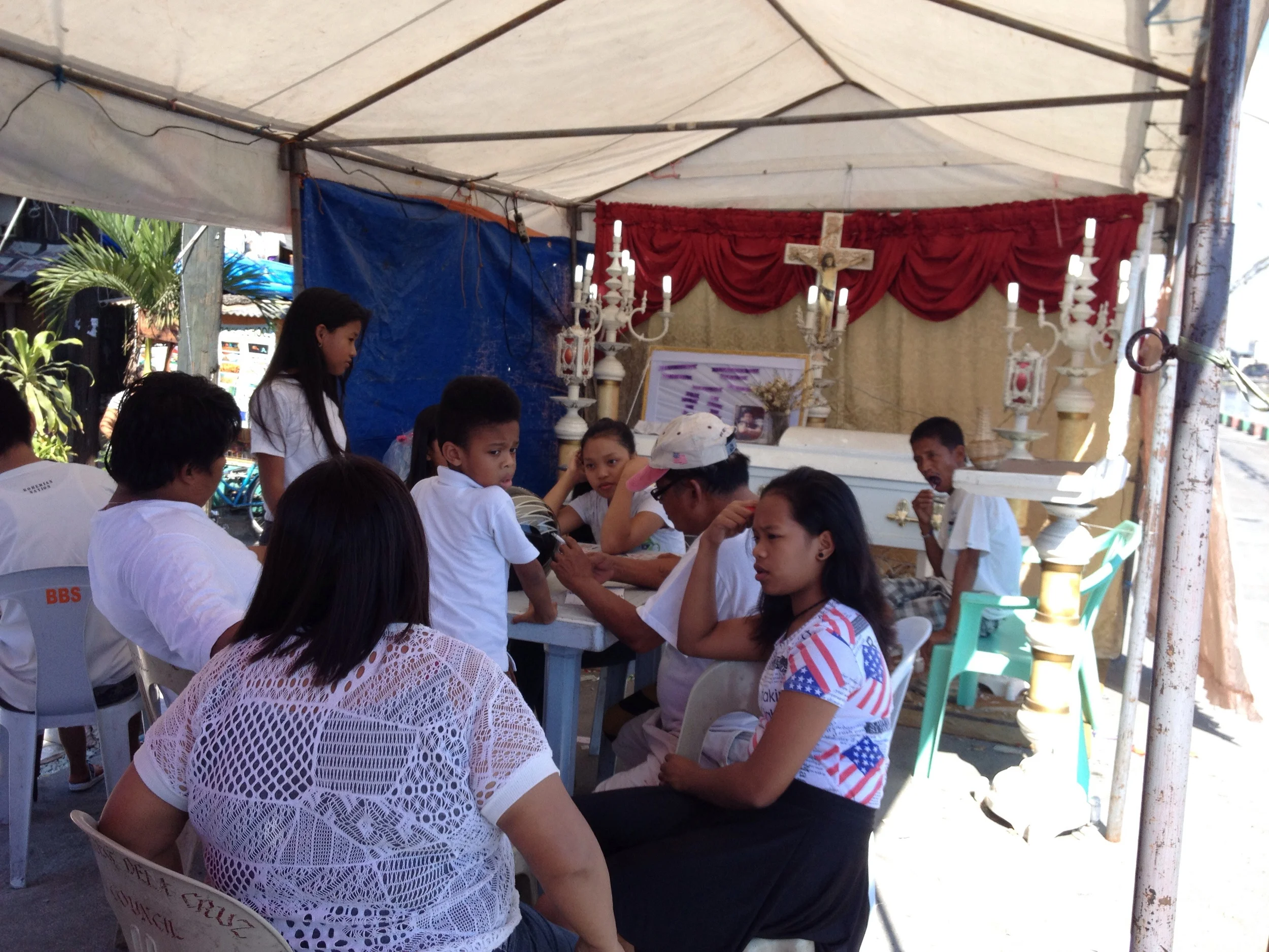 A wake in the Philippines lasts several days; families keep the spirit company until it passes to the afterlife. Here the wake is held along the river. 