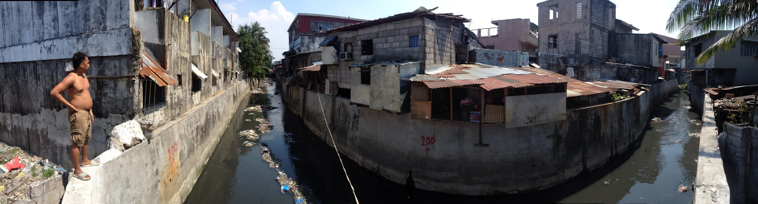 A man shows me the estero behind the Maypajo Market in Caloocan (South). The estero is lined with informal settlements that have been barricaded behind concrete walls. As we stand there I see an invisible hand throw a bag of trash from a house into the river. 