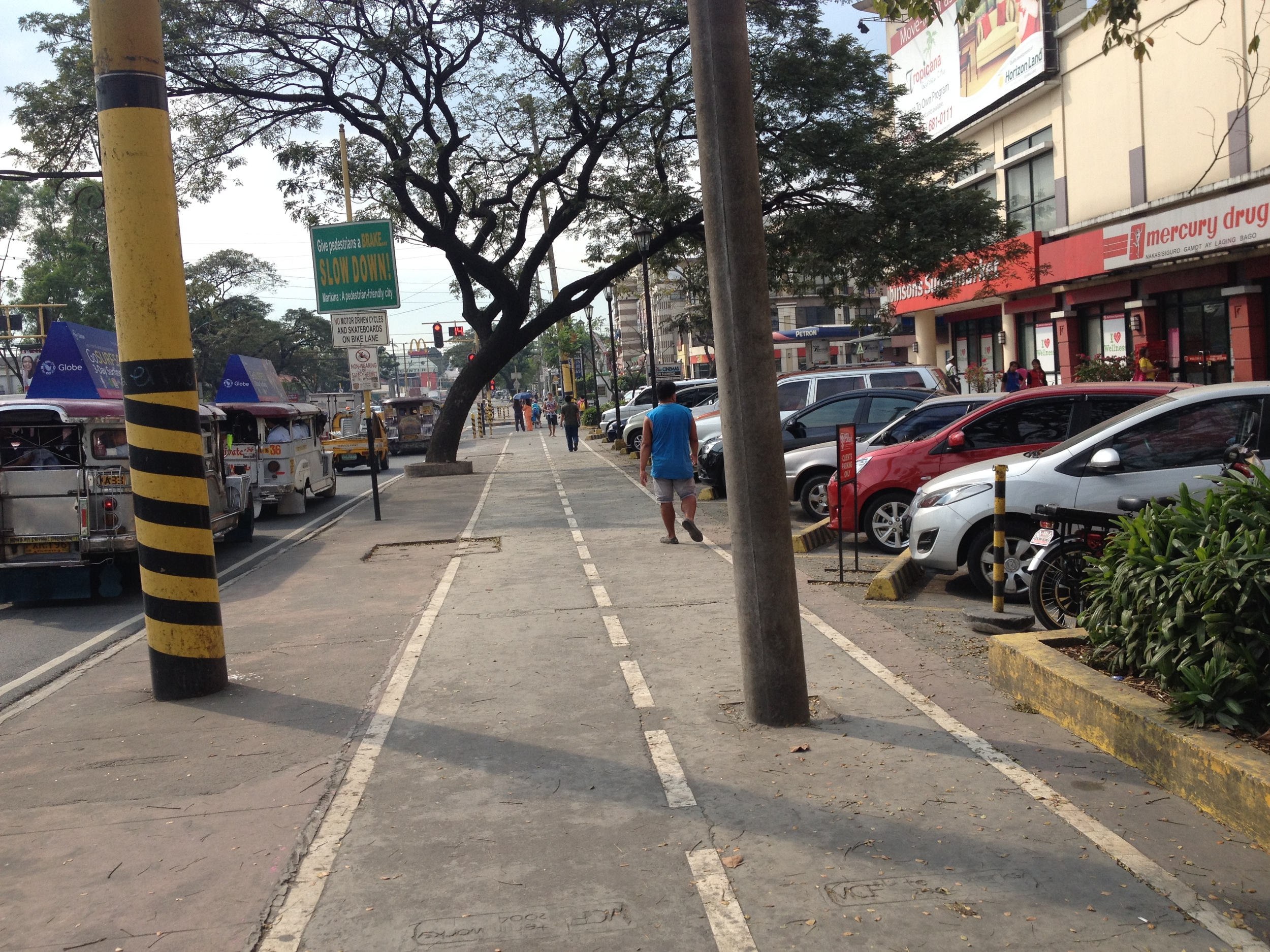 This sidewalk lane is less ideal since it has obstructions, but at least the parking is accessed from a separate area, which prevents cars from crossing the bike lane into a slot. 