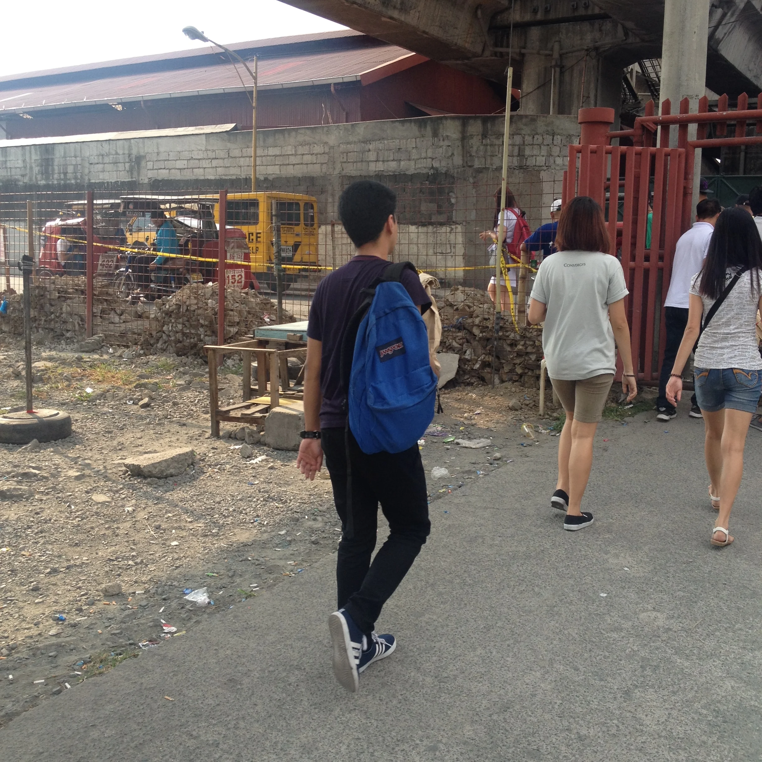 Commuters exit to a tricycle terminal outside the gate. 