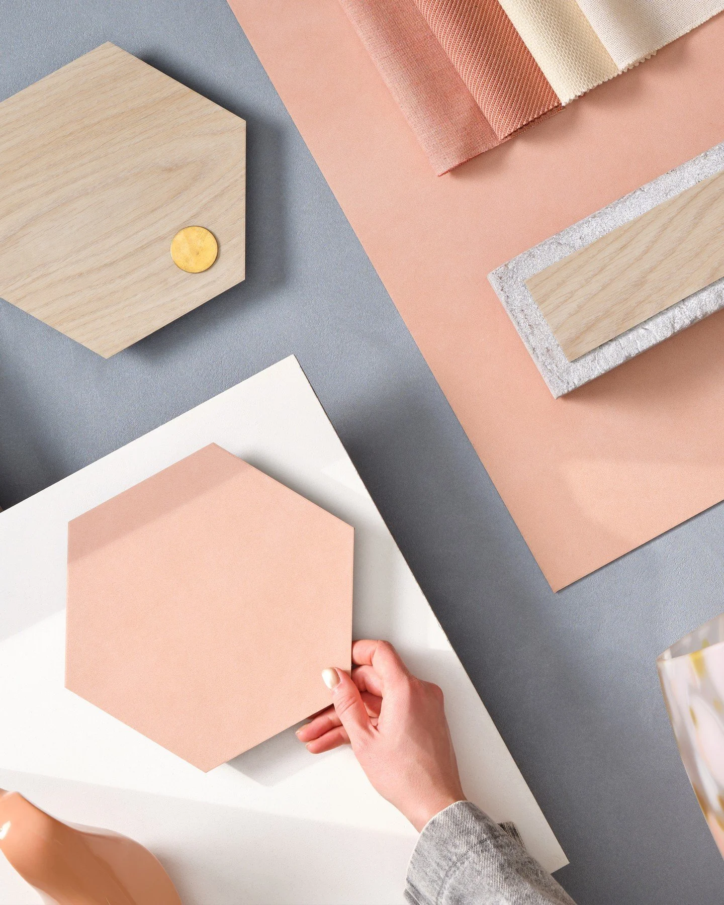 This mood board exudes warmth and tactility, combining peachy terracotta tones, soft greys, and natural wood textures for a welcoming, human-centered aesthetic. The interplay of hexagonal shapes, fabric swatches, and handcrafted finishes introduces a