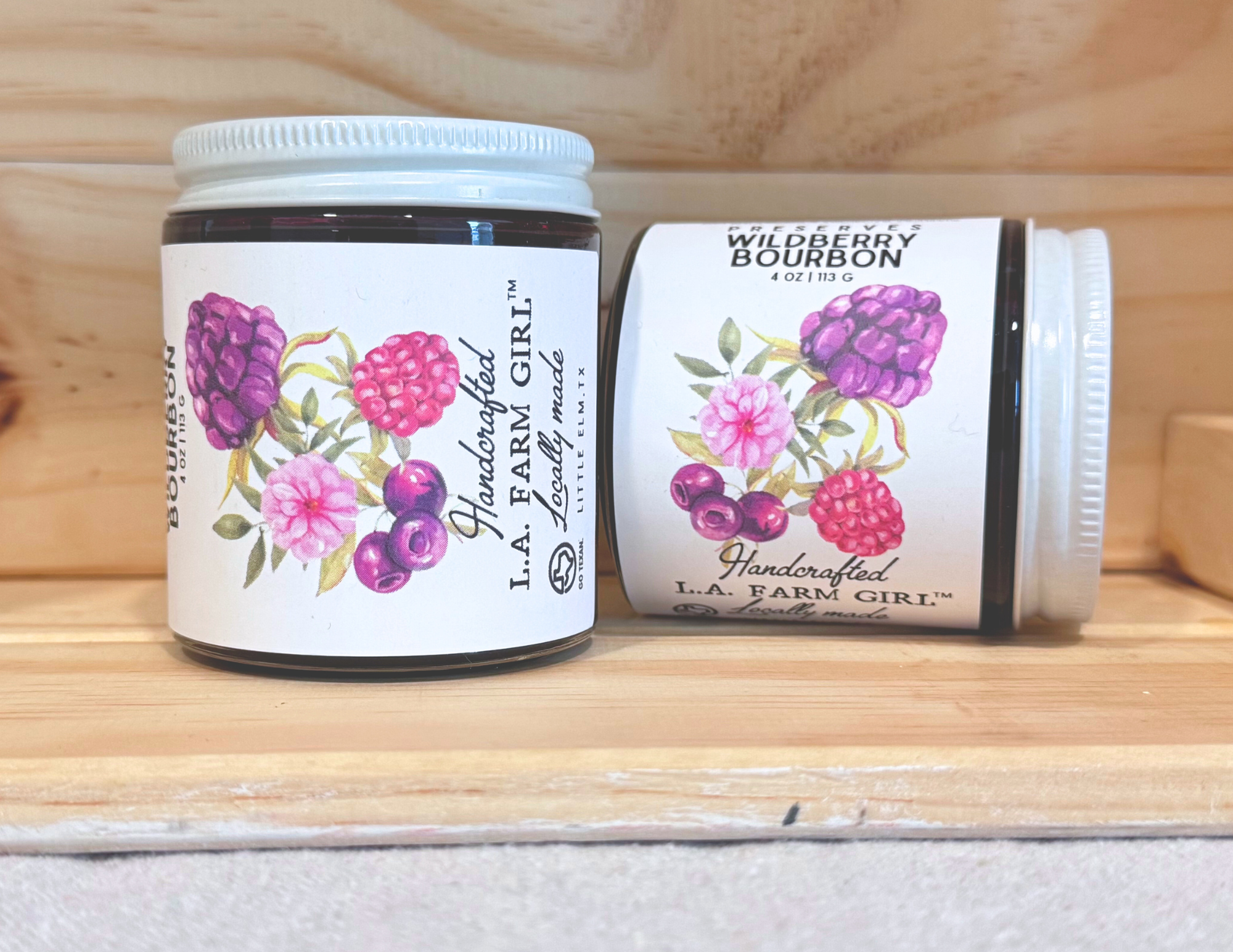 Wildberry Bourbon preserves jar with illustrated berry label on wooden shelf.