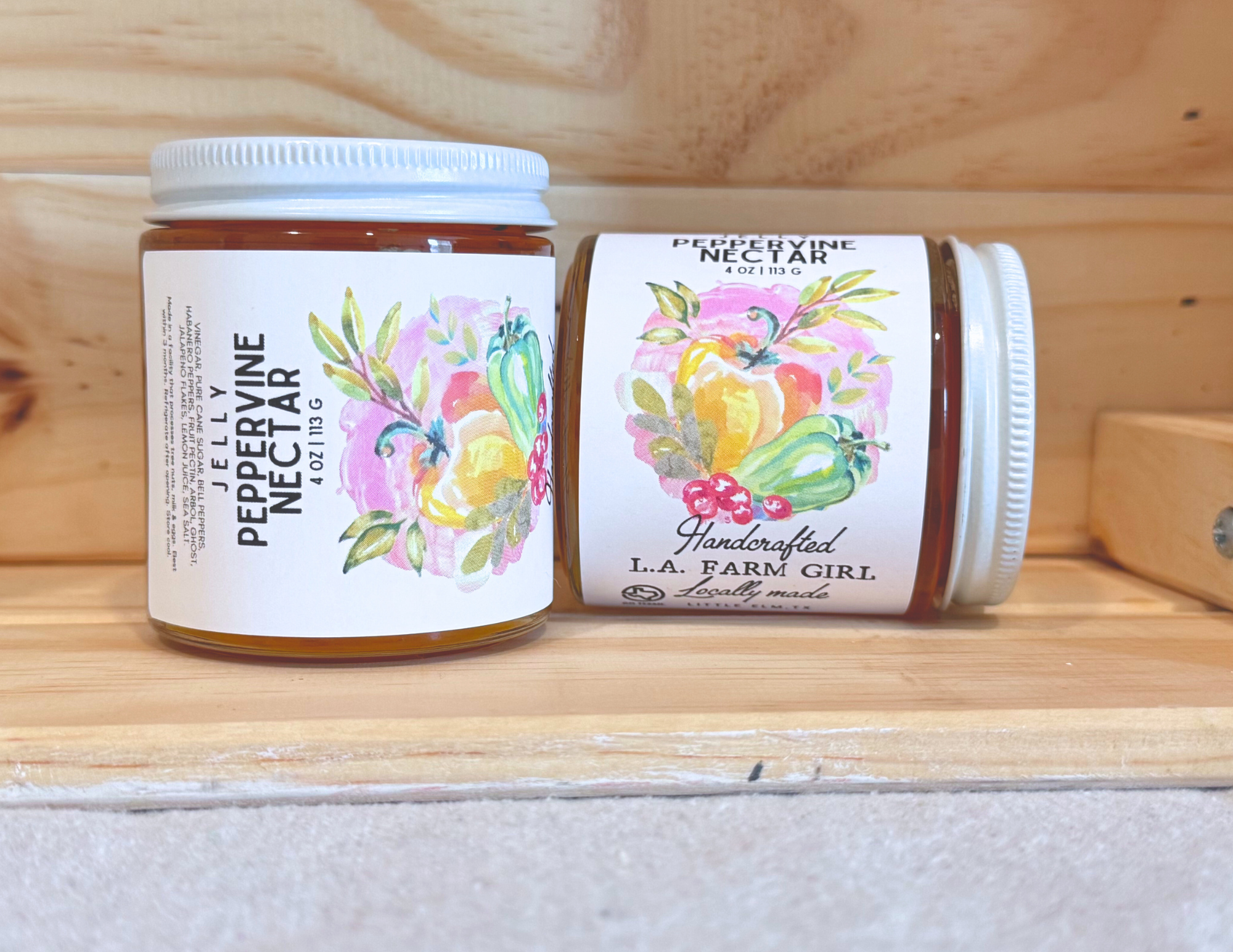 Peppervine Nectar jelly jar displayed upright and sideways on wooden shelf.
