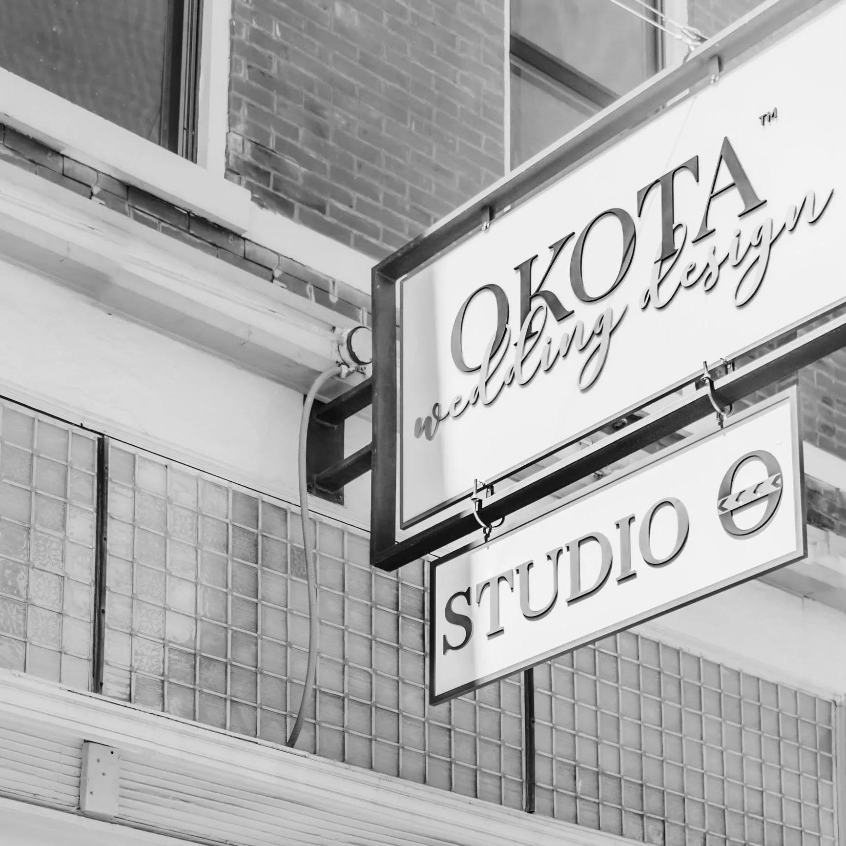 OKOTA storefront signage shown in black and white from below.
