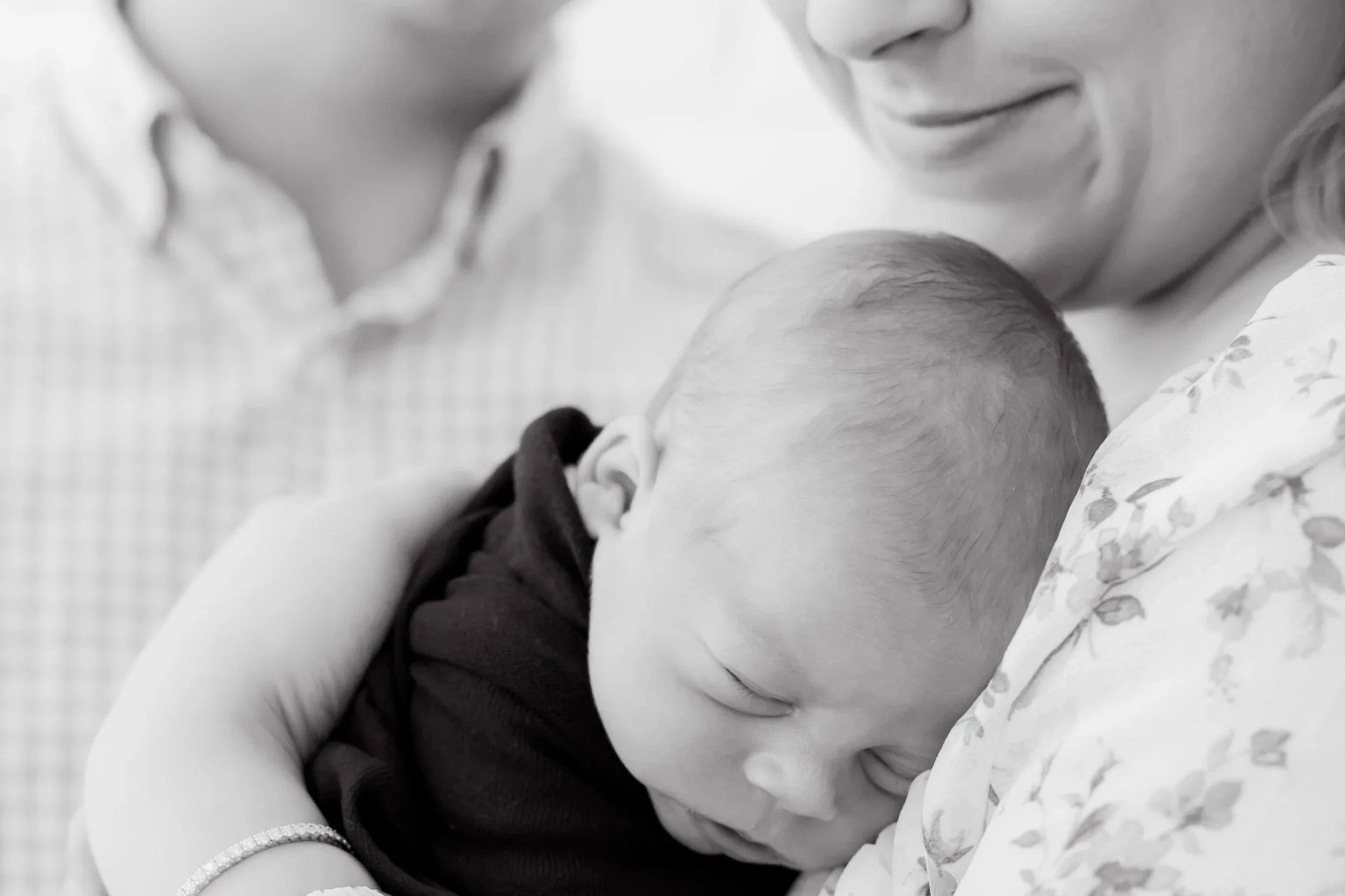 Black and white image of couple holding a newborn baby.