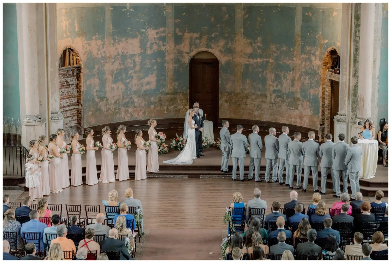 Wide angle image of the entire bridal party lined up at the altar for the wedding ceremony inside the Monastery Event Center in Cincinnati.