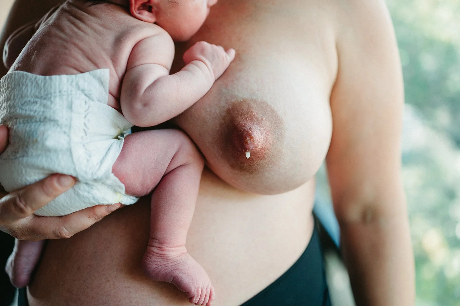 Mother holding newborn milk dripping