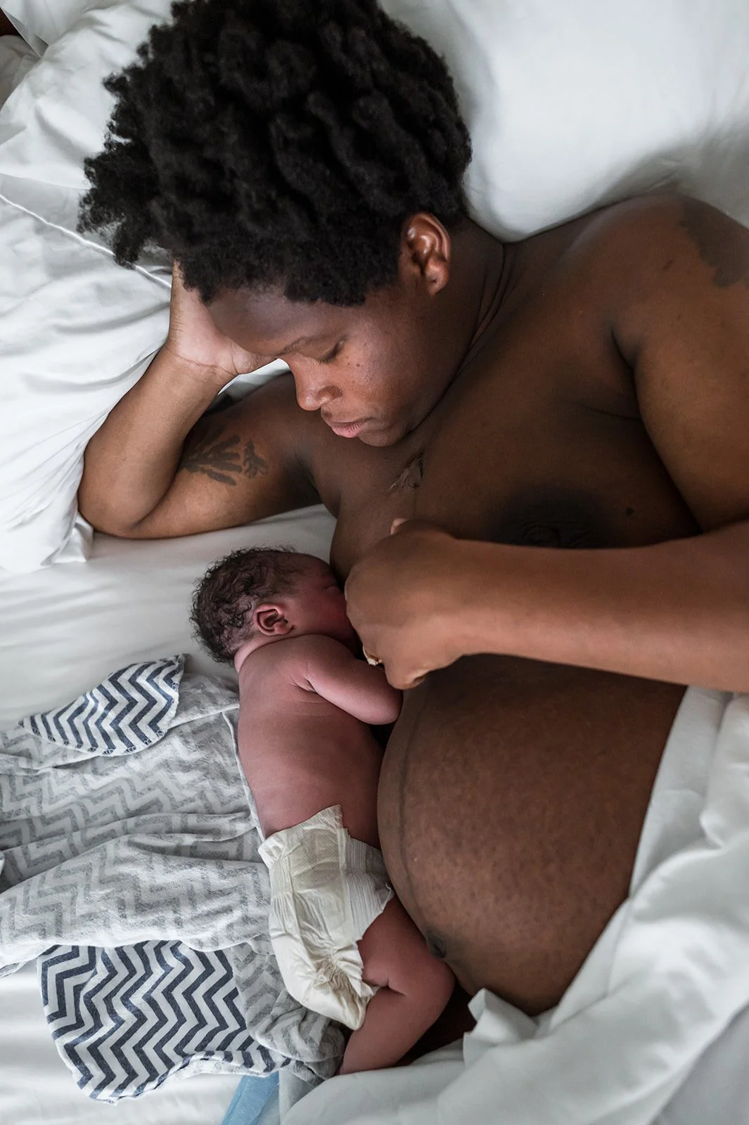 Mother breastfeeding newborn in bed